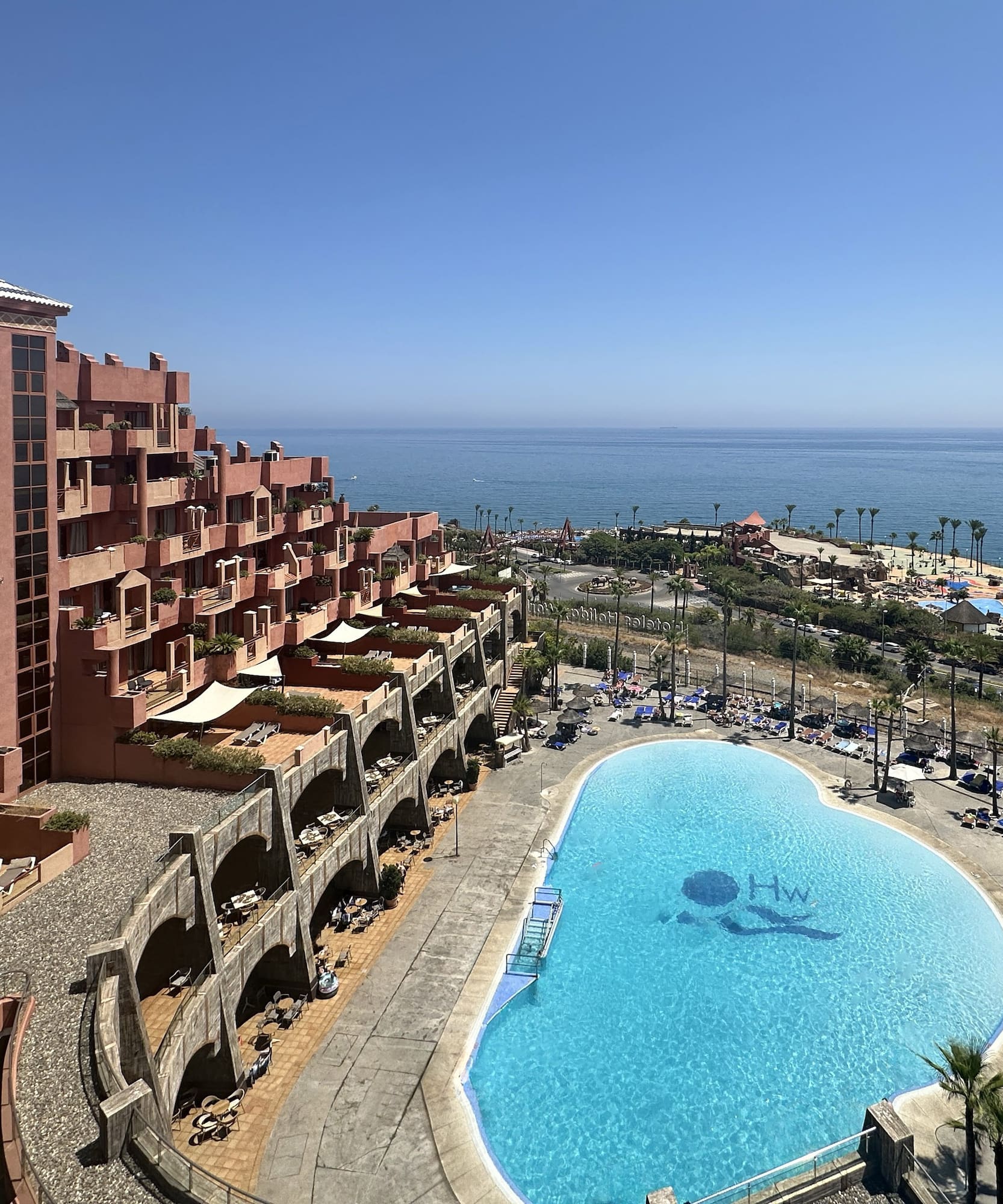 a pool with a large building and a beach