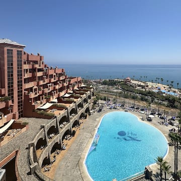 a pool with a large building and a beach