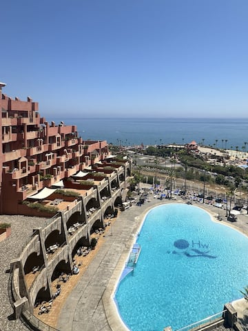 a pool with a large building and a beach