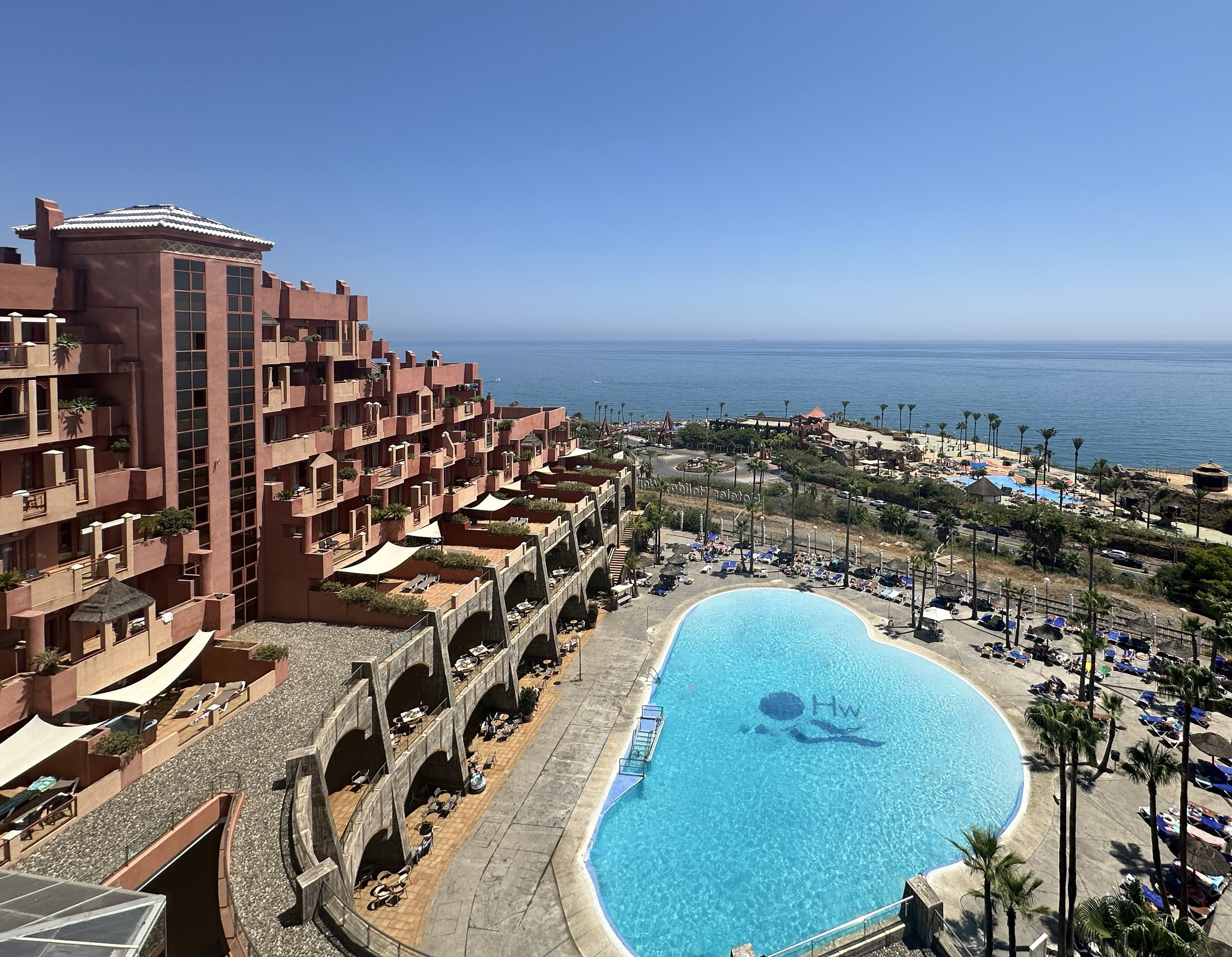 a pool with a large building and a beach