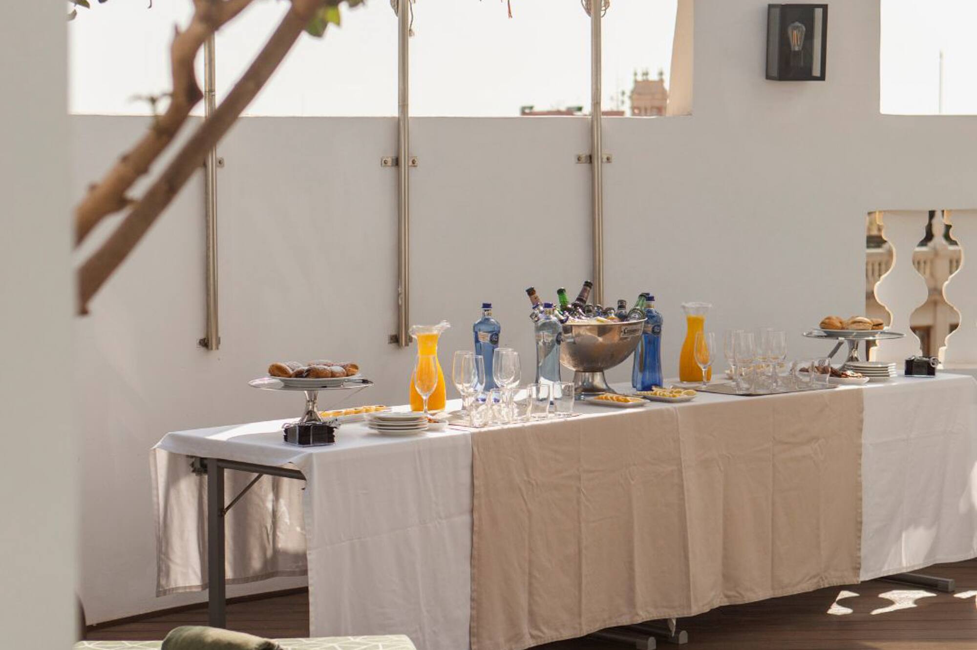 Rooftop terrace table with drinks, orange juice, and pastries for outdoor brunch.