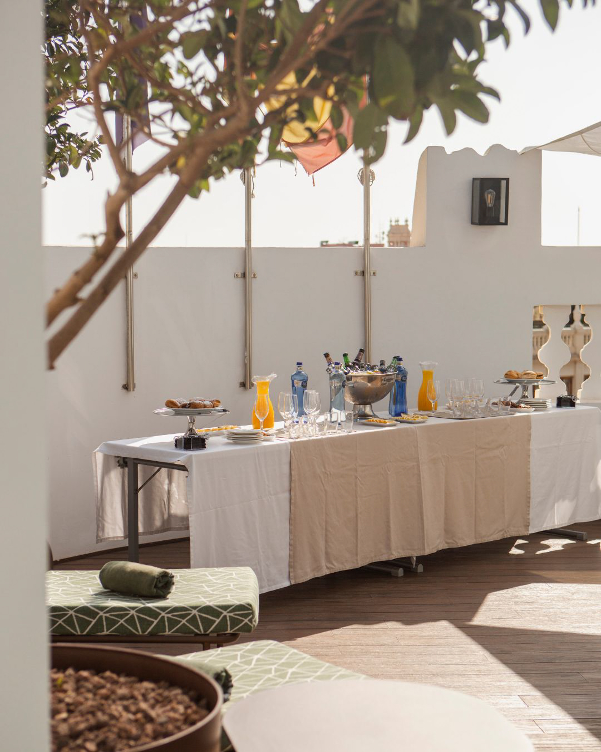 Rooftop terrace table with drinks, orange juice, and pastries for outdoor brunch.