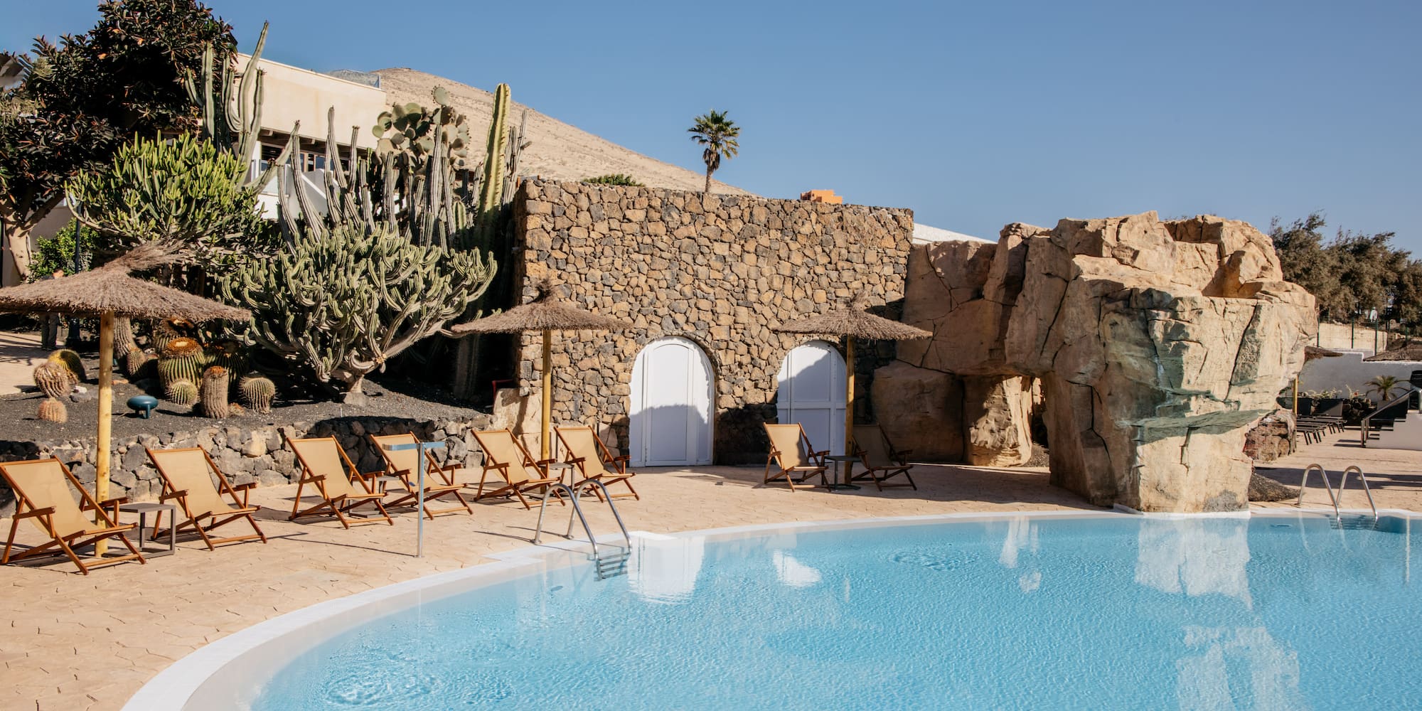 a pool with chairs and a stone wall