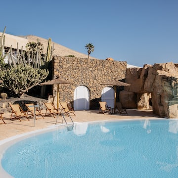 a pool with chairs and a stone wall