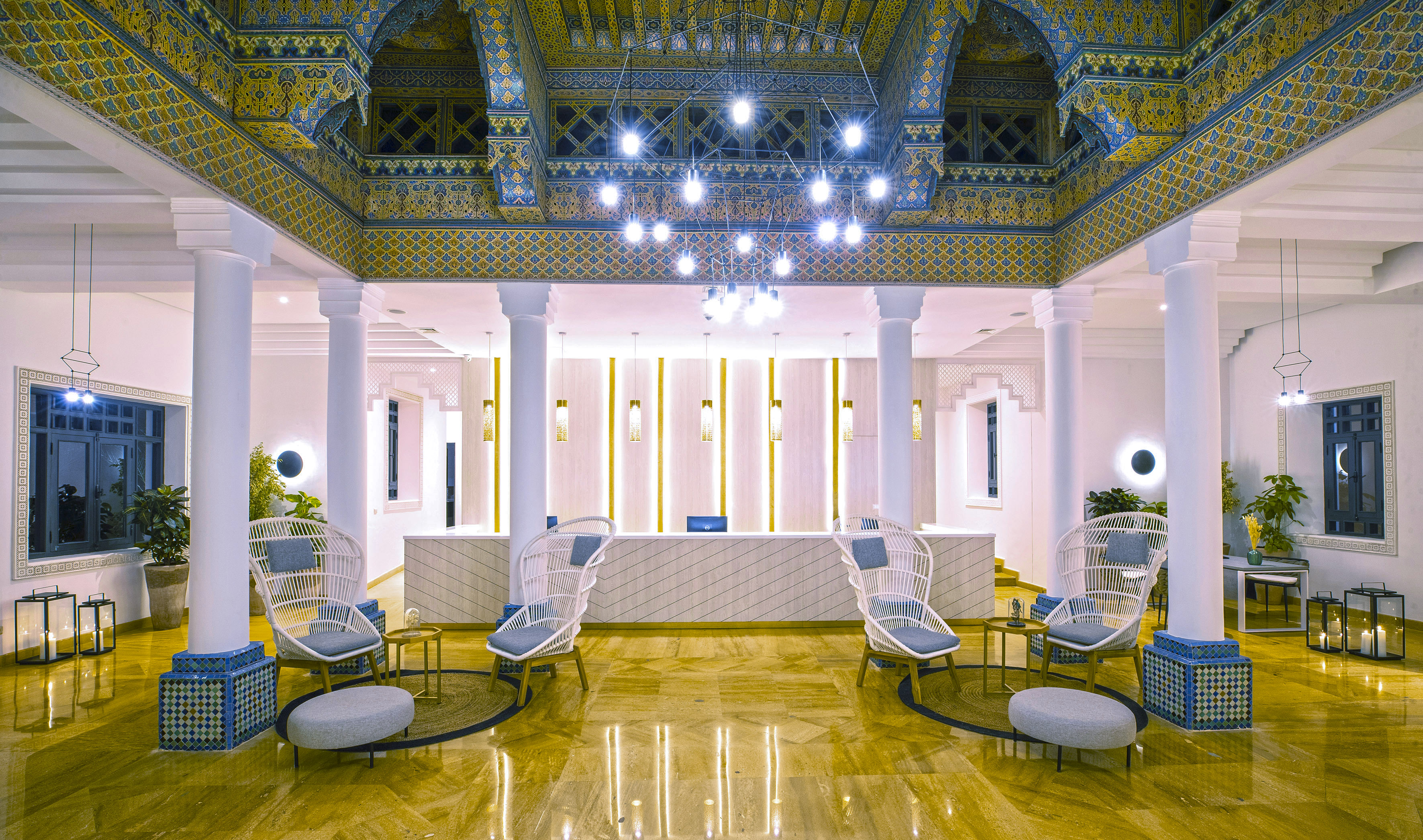 Luxurious hotel lobby with ornate Moroccan ceiling, reception, and modern lounge seating.