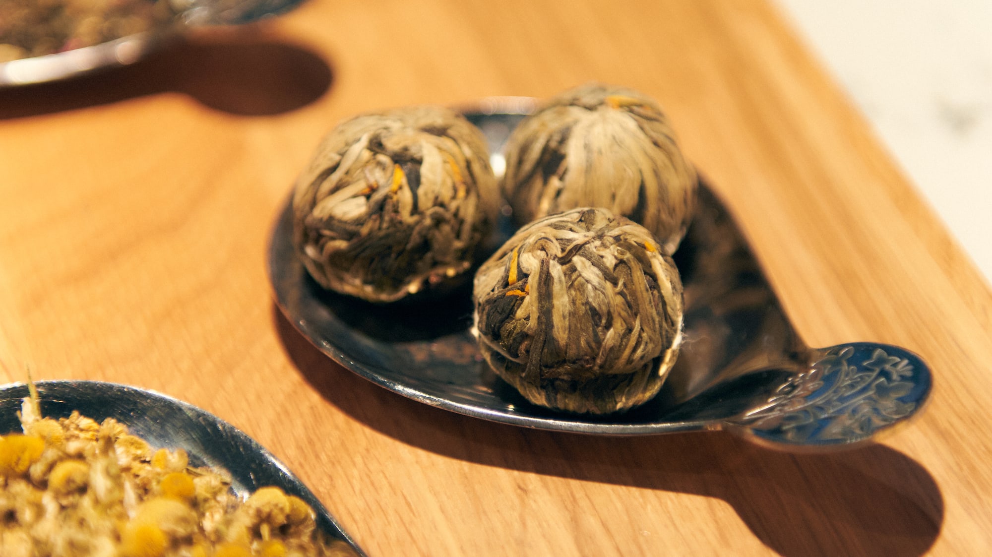 a group of silver spoons with herbs on them