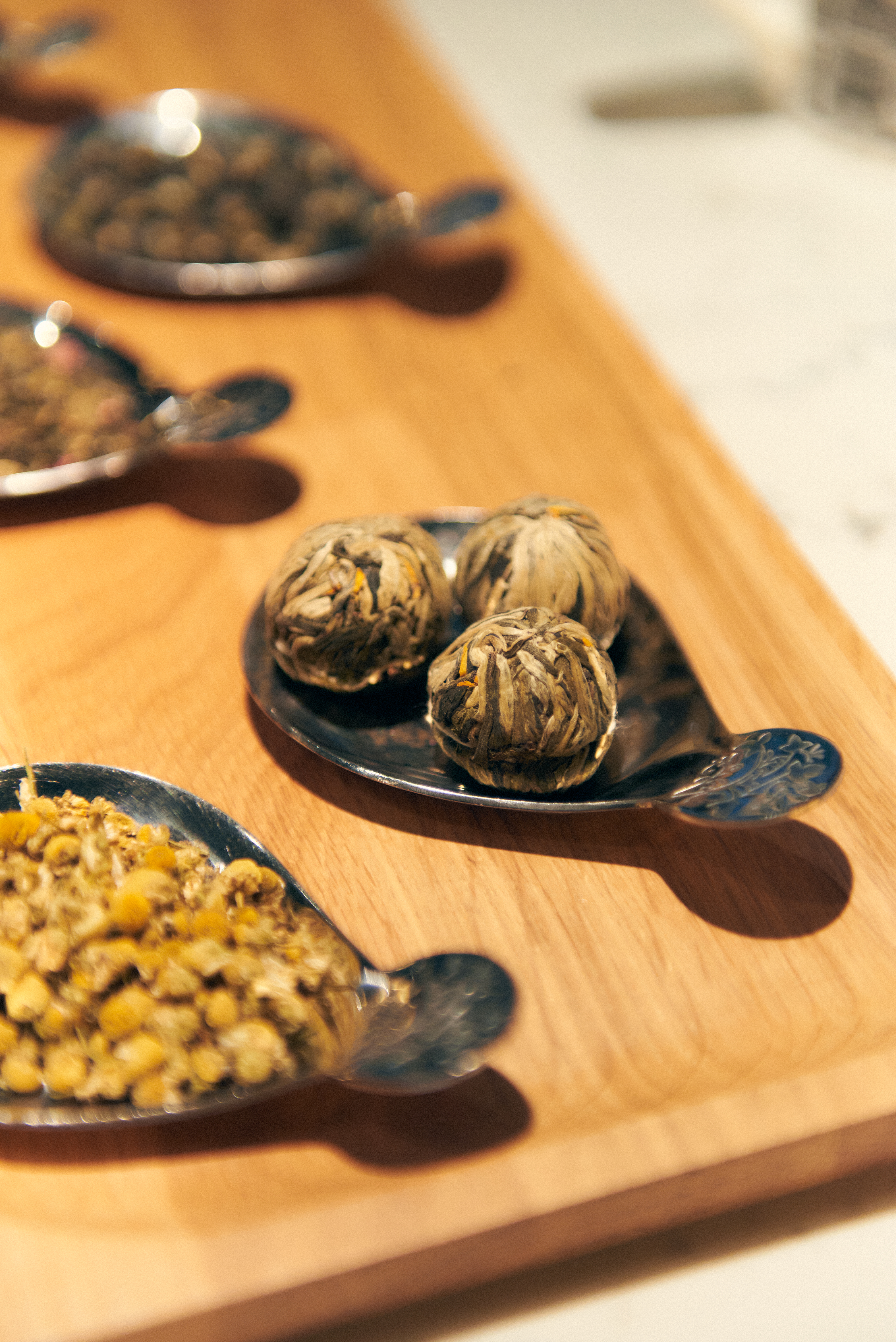a group of silver spoons with herbs on them