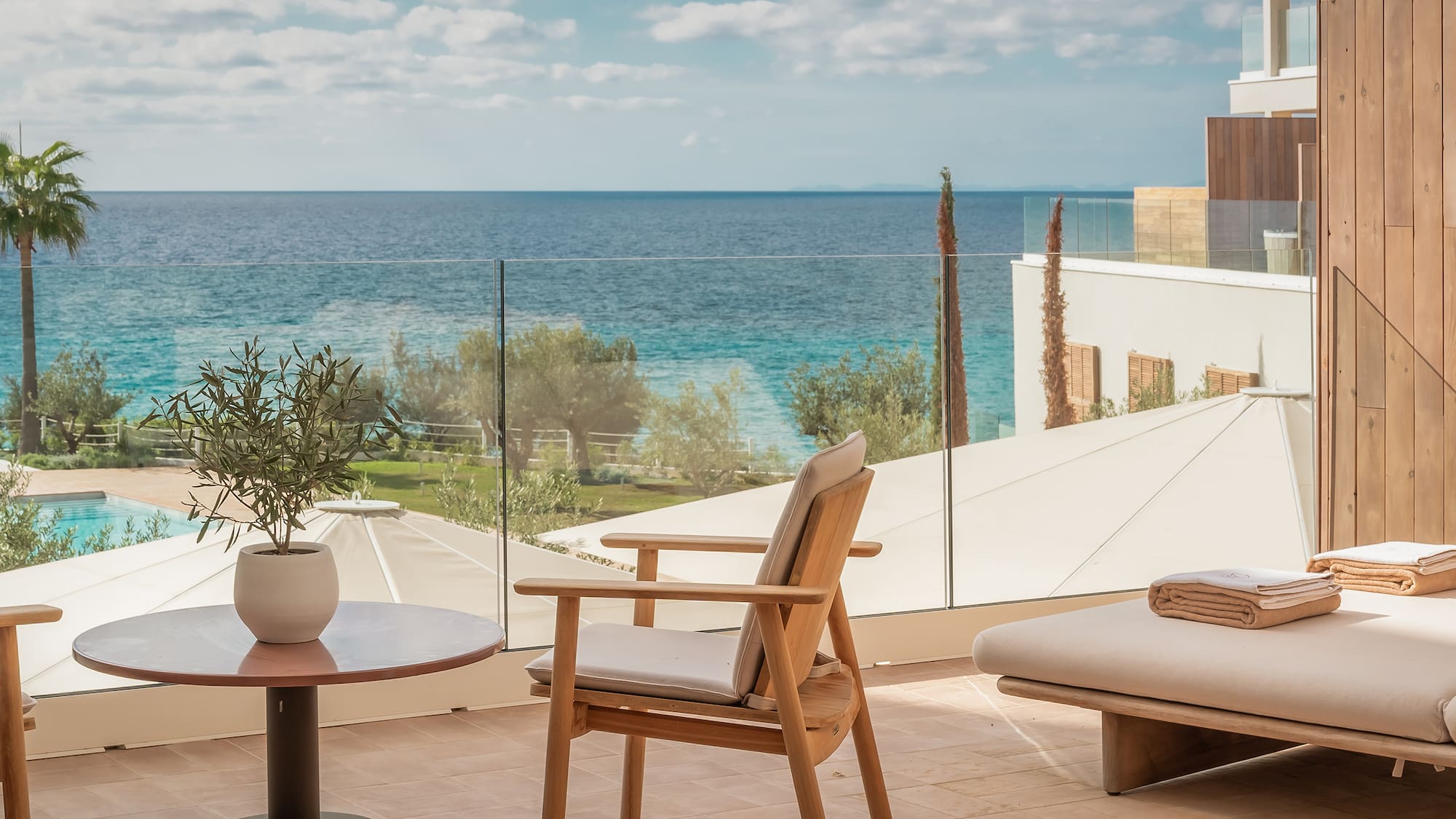 a chair and table on a balcony overlooking a body of water