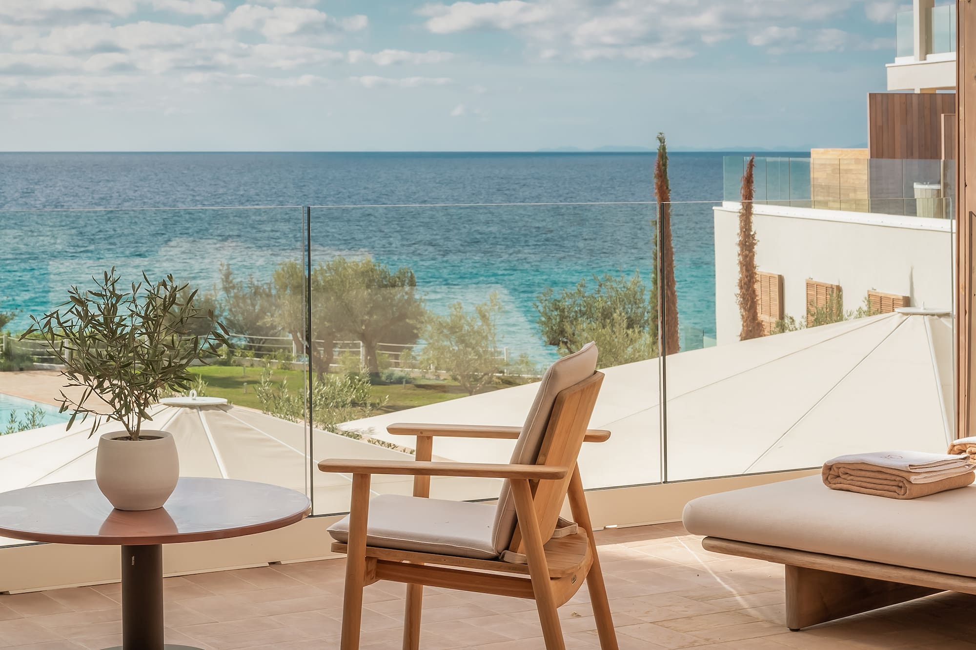 a chair and table on a balcony overlooking a body of water