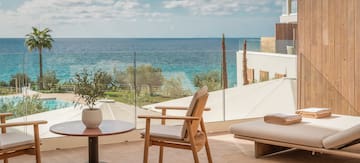 a chair and table on a balcony overlooking a body of water