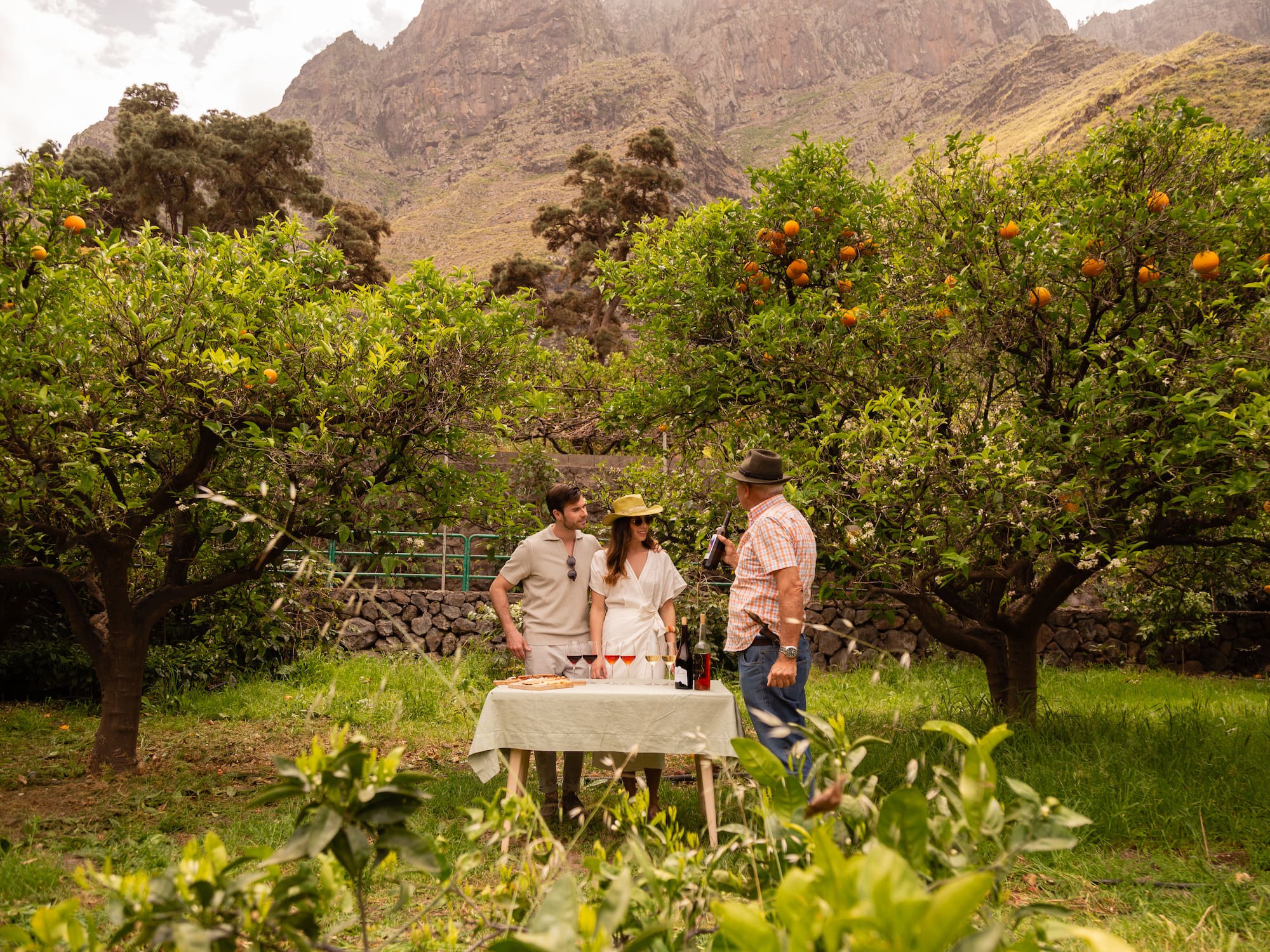 a group of people standing outside at a table with food and drinks