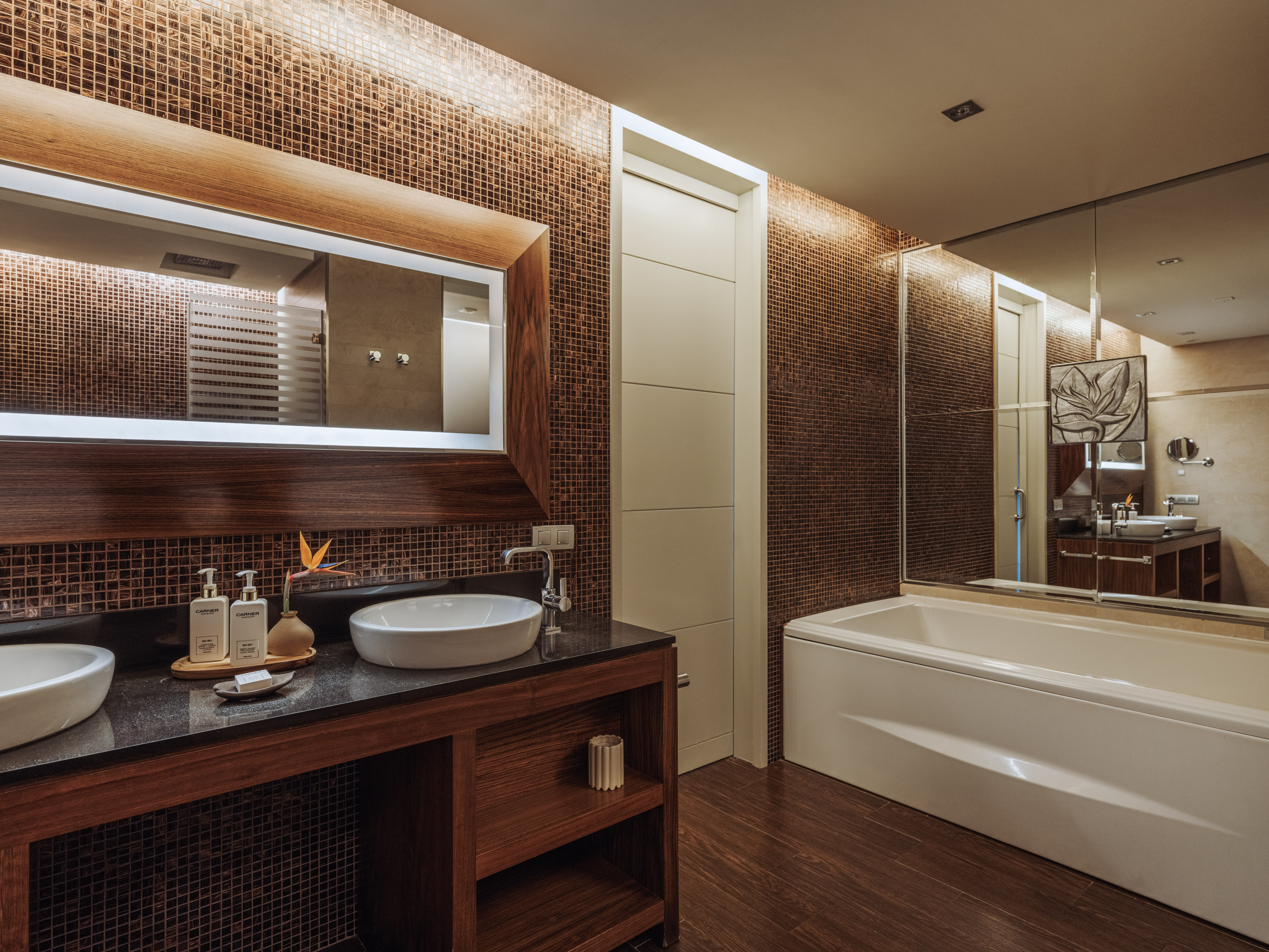 Luxury modern bathroom with mosaic walls, double vessel sinks, and bathtub.