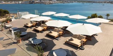 a group of chairs and umbrellas on a deck overlooking a body of water