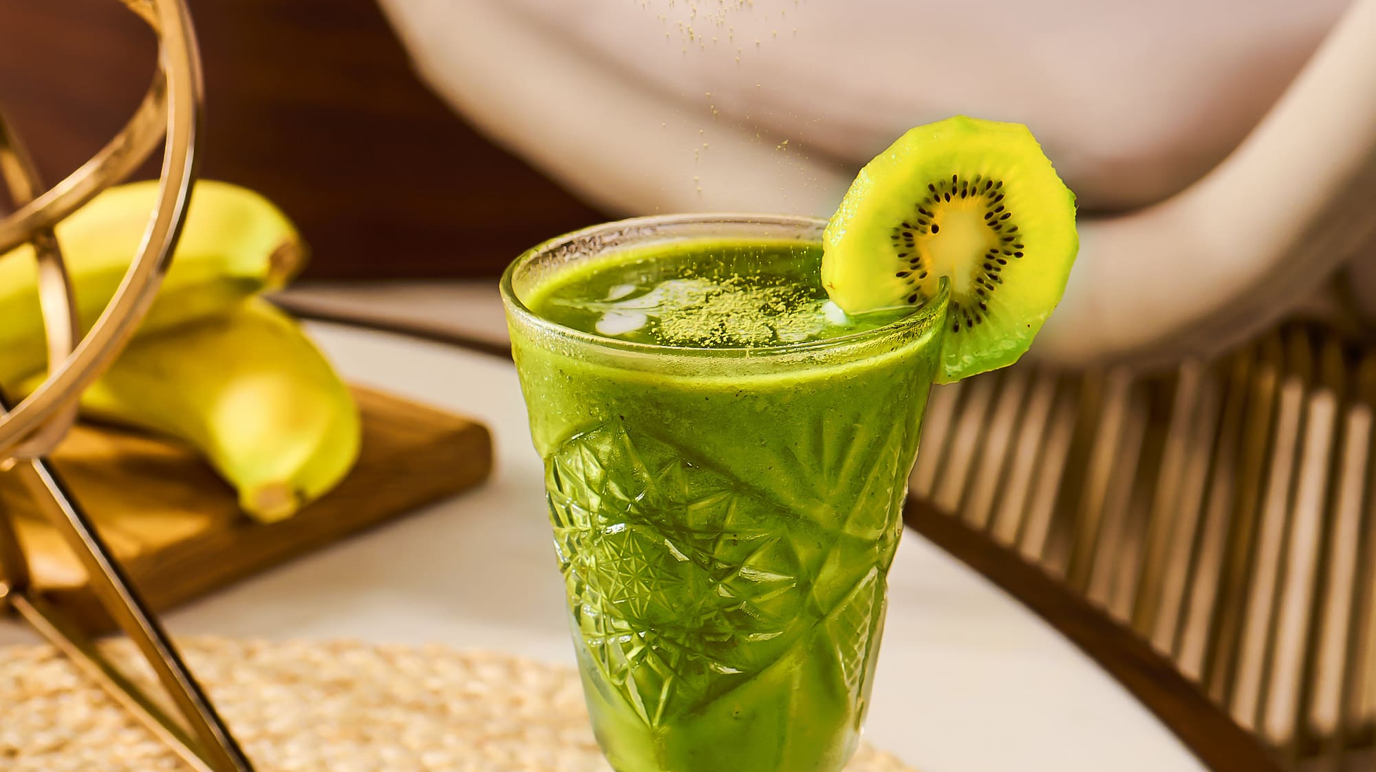 a person pouring a kiwi into a glass of drink