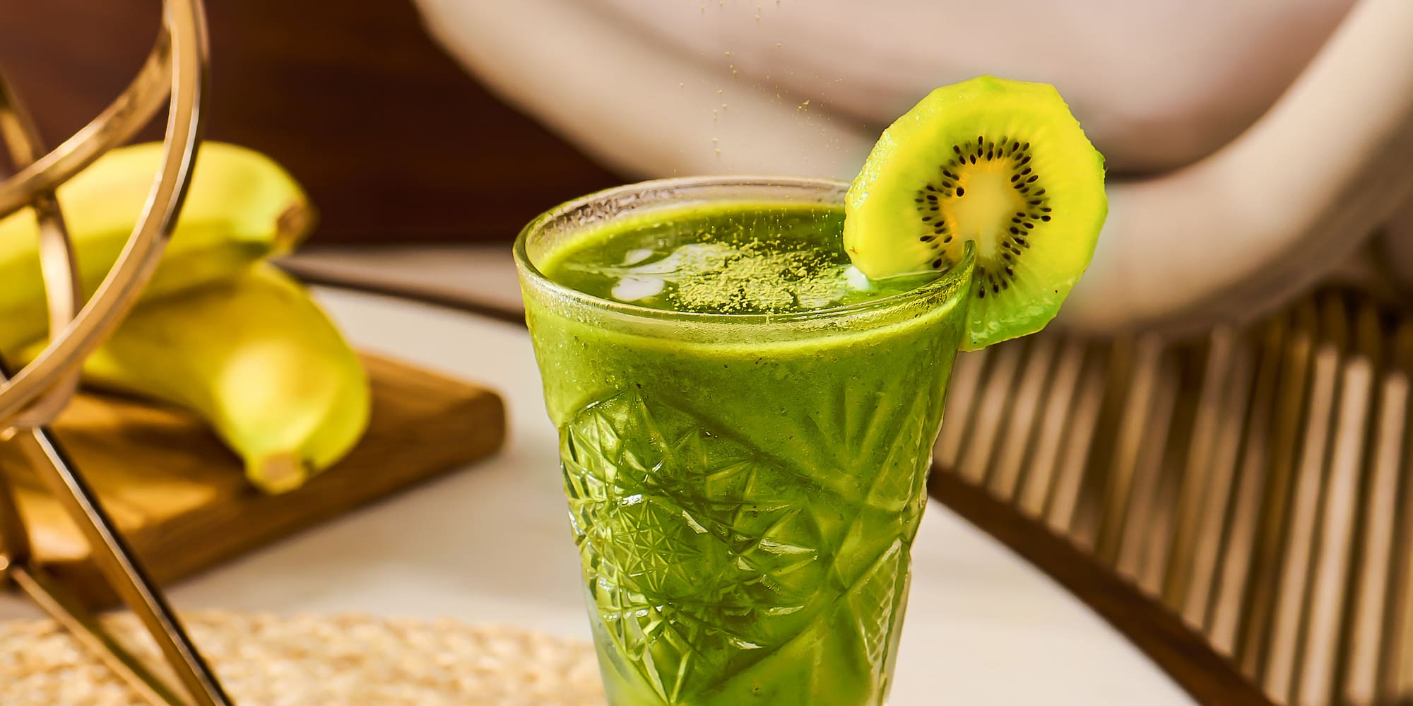a person pouring a kiwi into a glass of drink