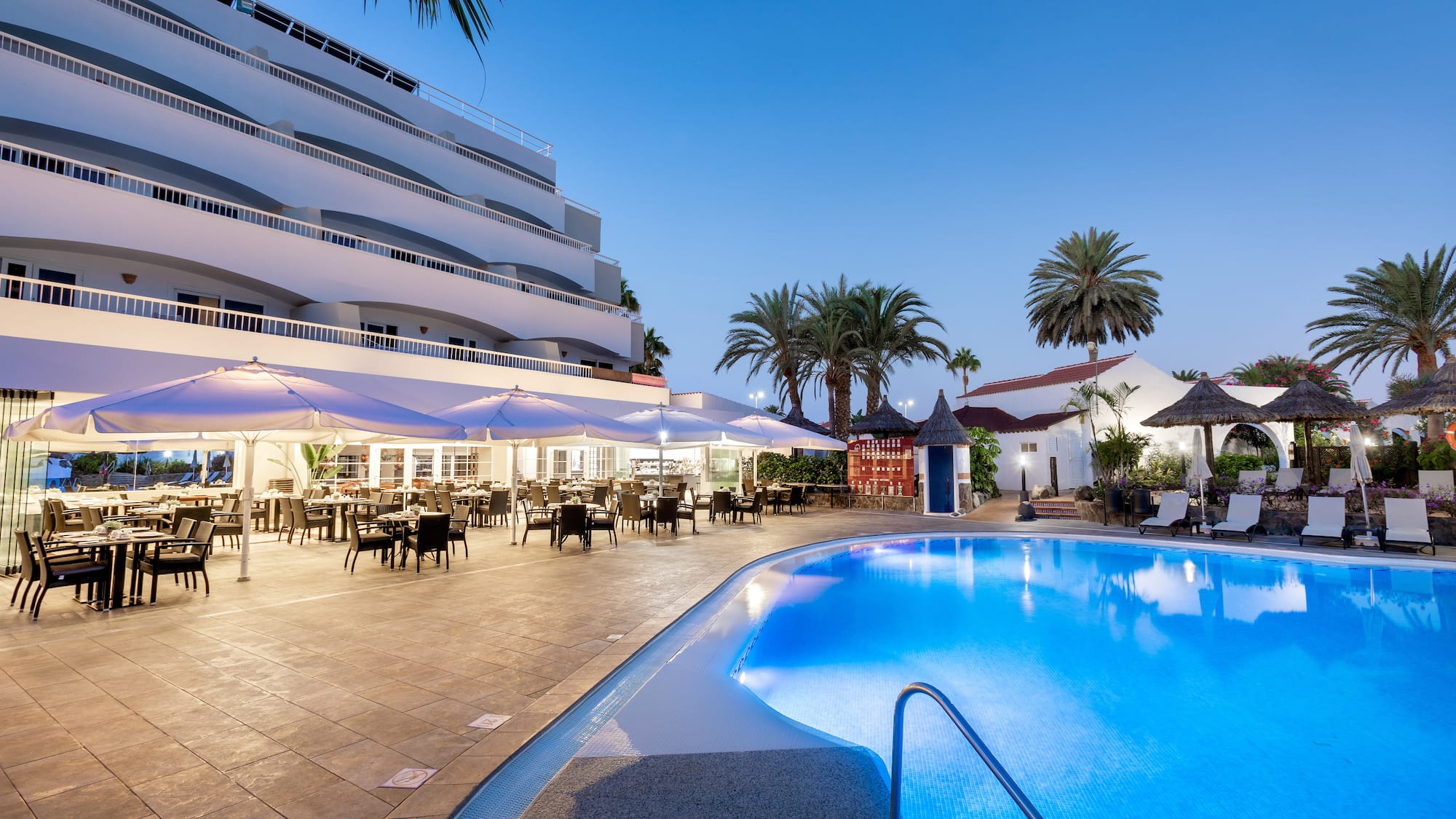 a pool with tables and chairs in front of a building