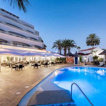 a pool with tables and chairs in front of a building