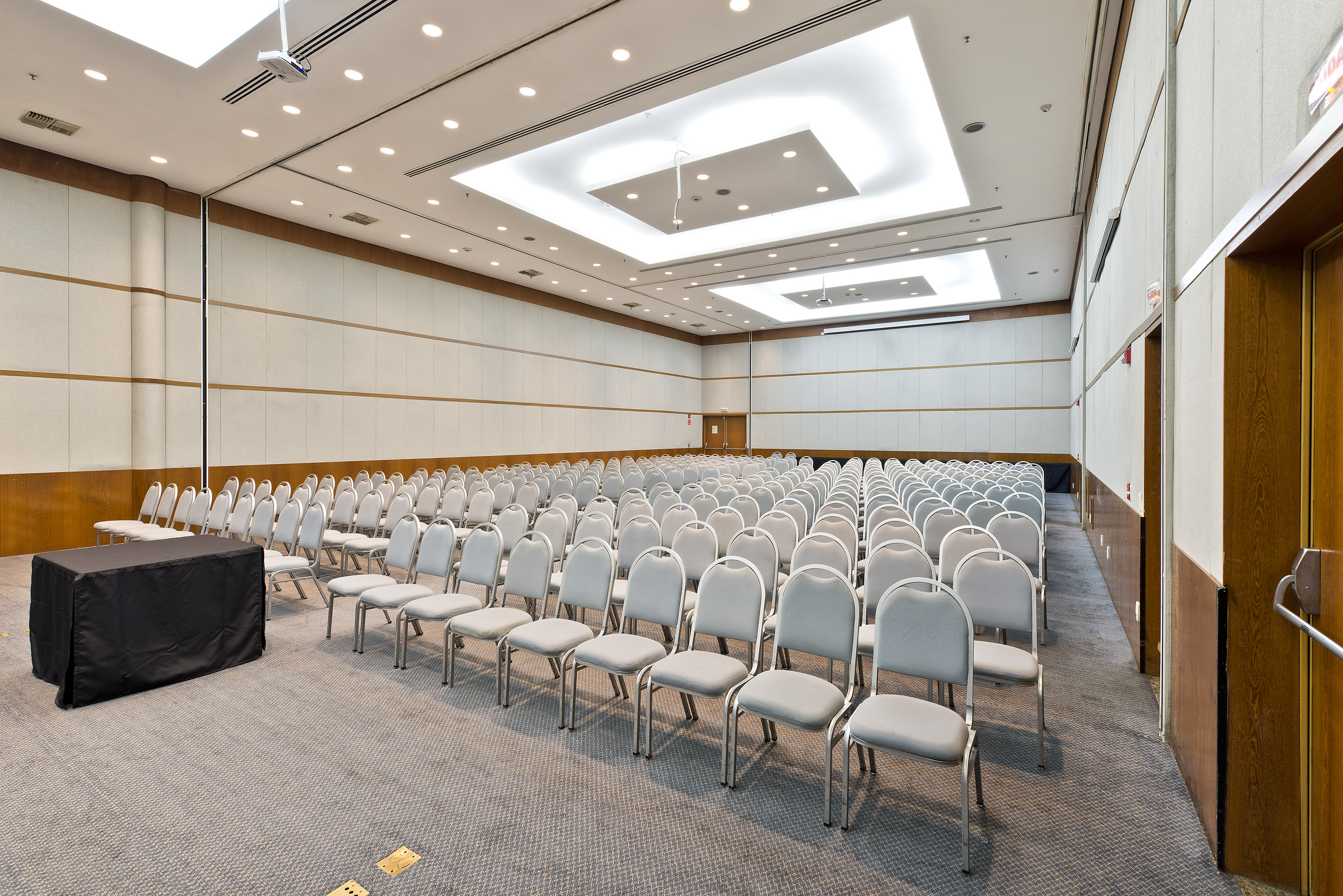 Spacious empty conference room with auditorium seating and ceiling projector.