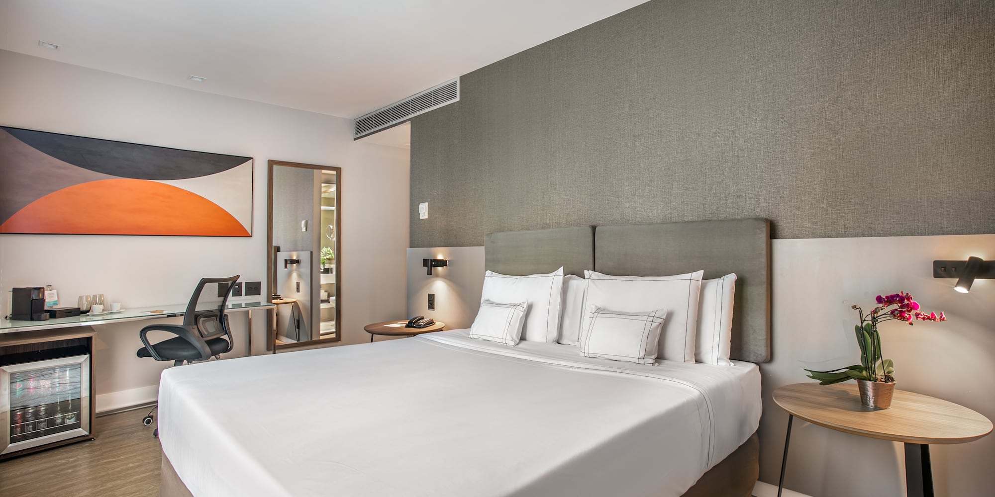 a bed with white sheets and a table with lamp and chair