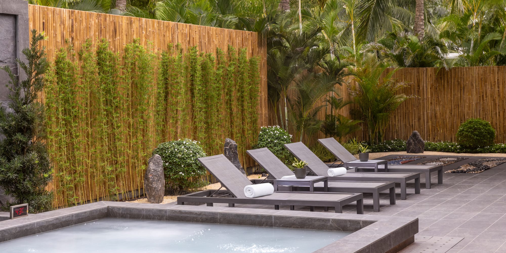 Resort jacuzzi, loungers, bamboo screen, and tropical plants.