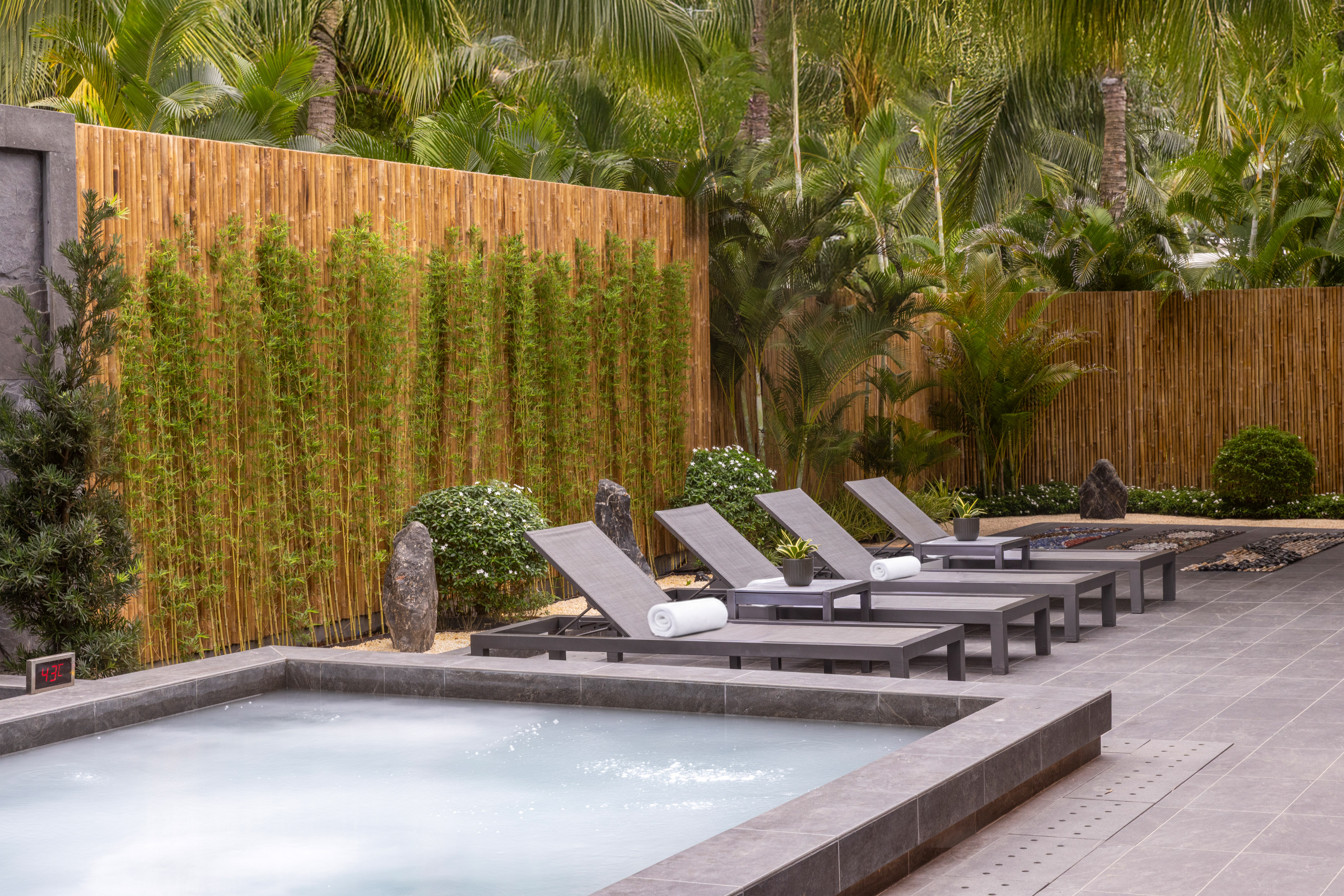 Resort jacuzzi, loungers, bamboo screen, and tropical plants.