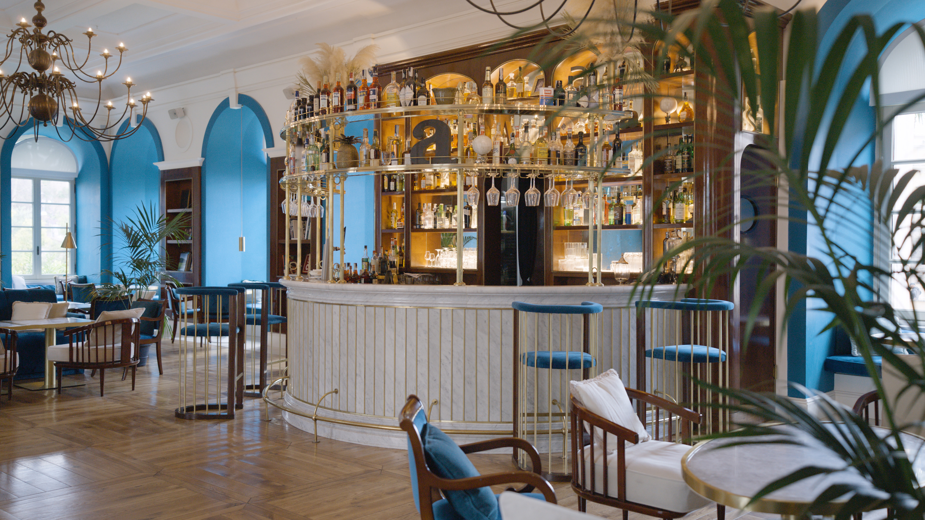 Elegant luxury bar with marble counter, brass shelving, and blue accents.