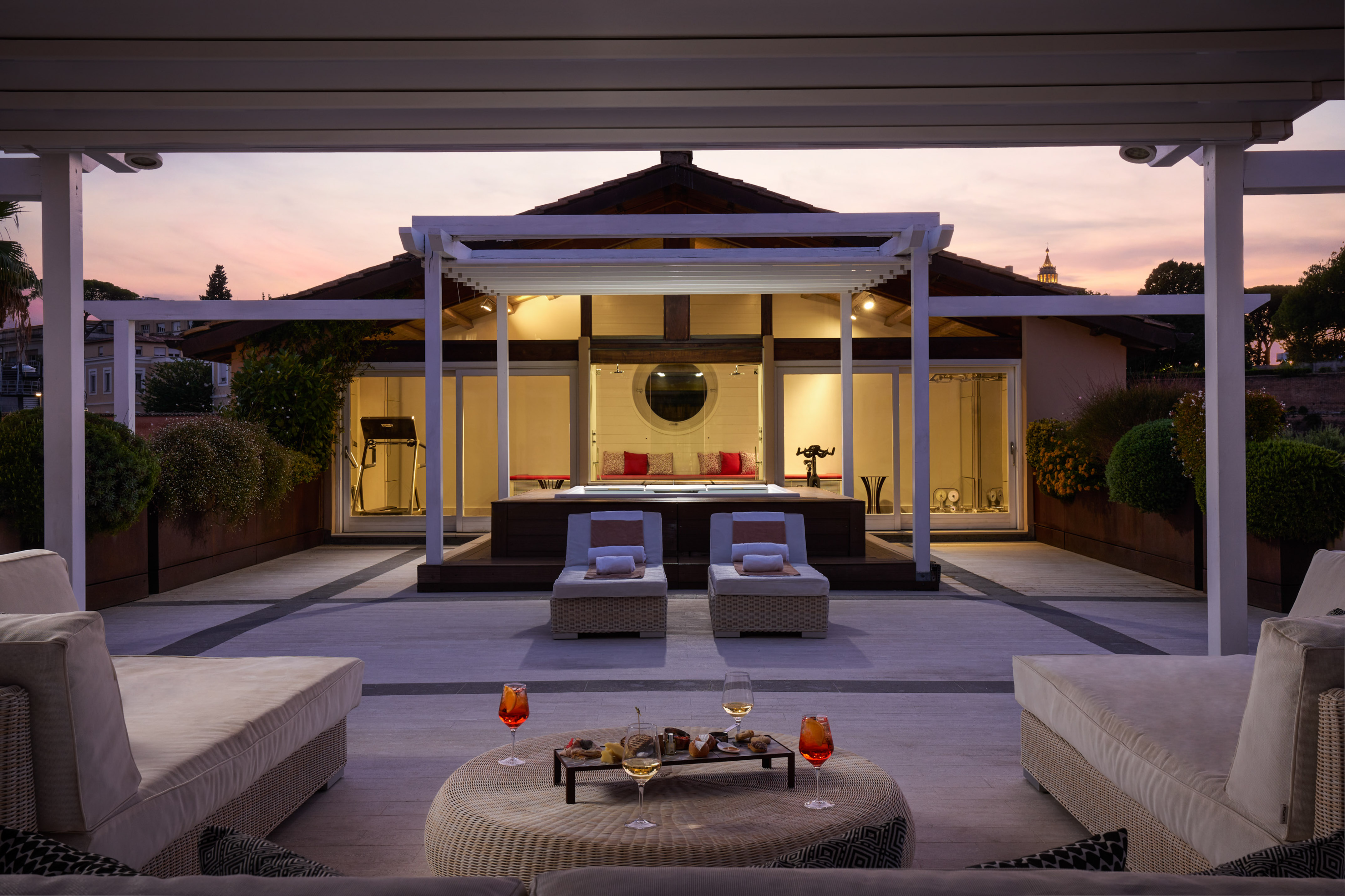 Luxury rooftop terrace with private spa, lounge chairs, and aperitivo at sunset.