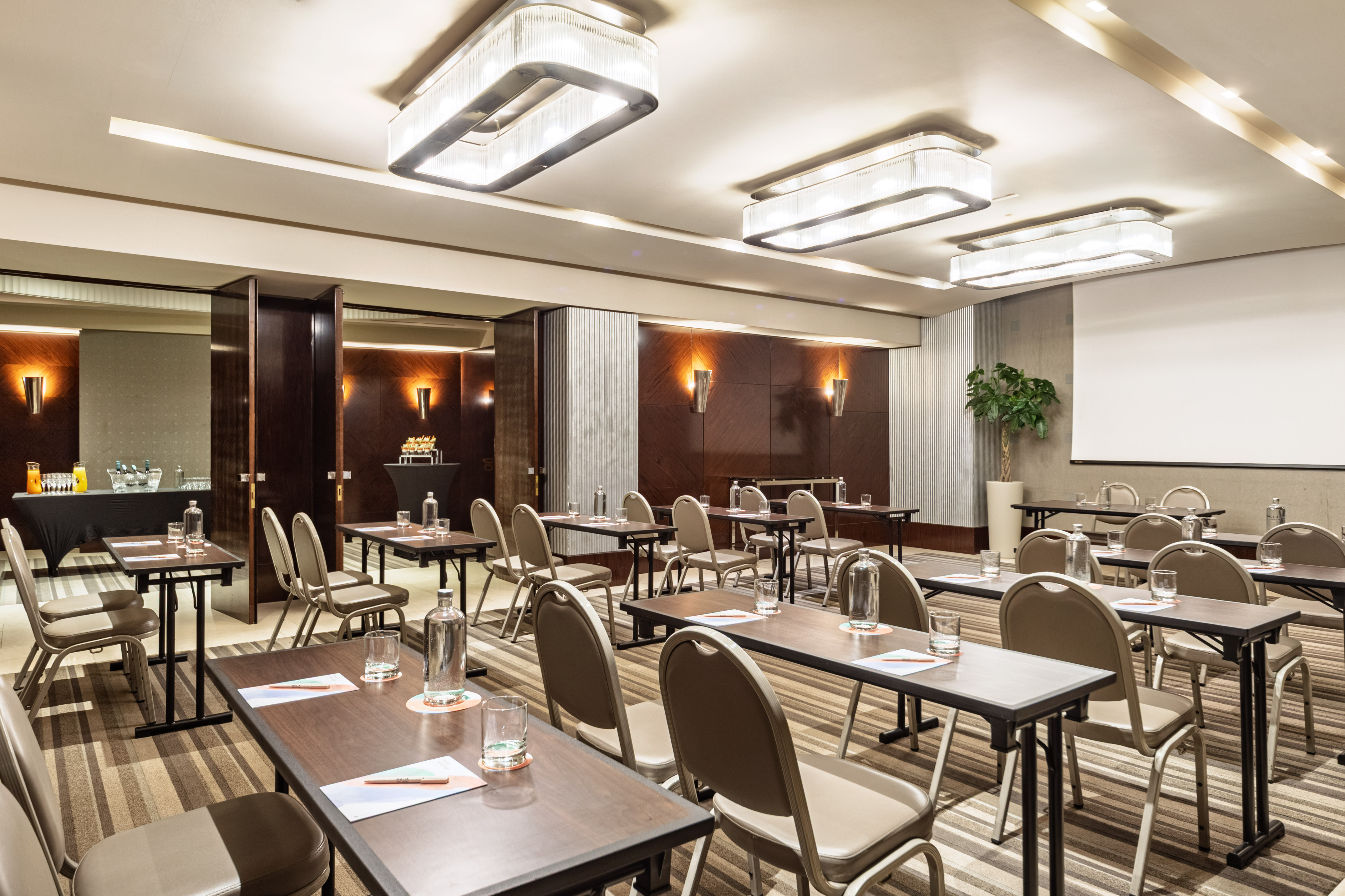 Hotel meeting room with individual tables, chairs, and presentation screen.
