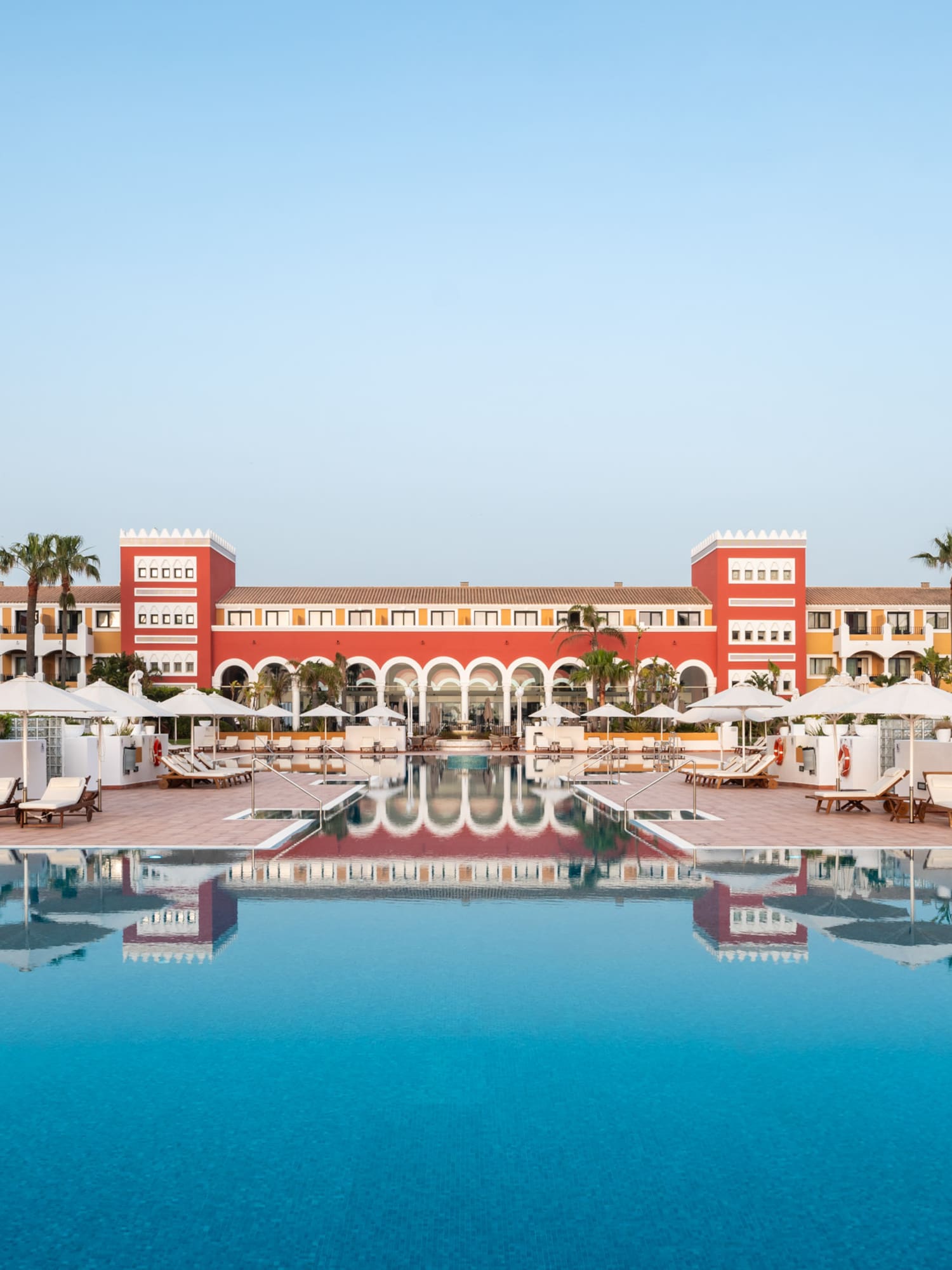 a pool with umbrellas and chairs in front of a building