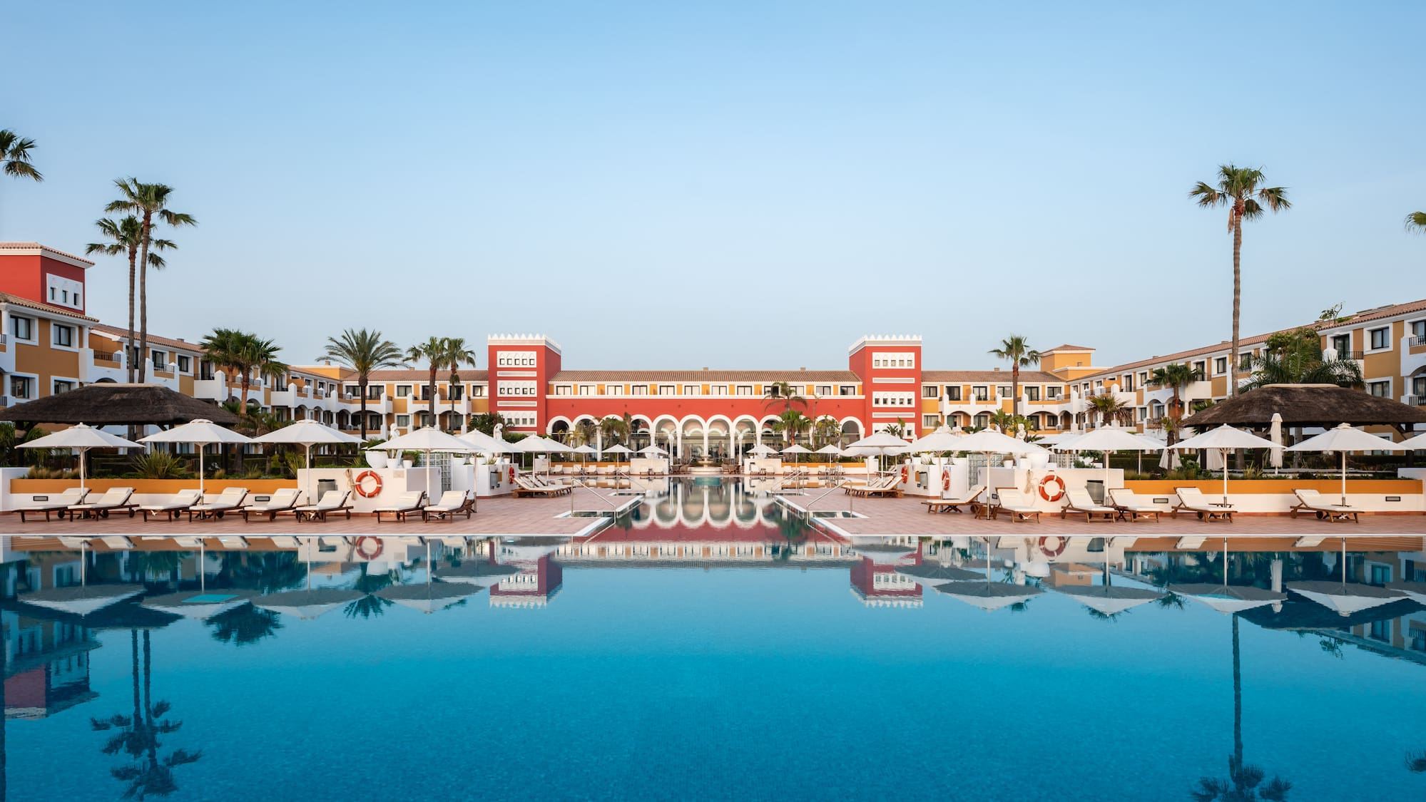 a pool with umbrellas and chairs in front of a building