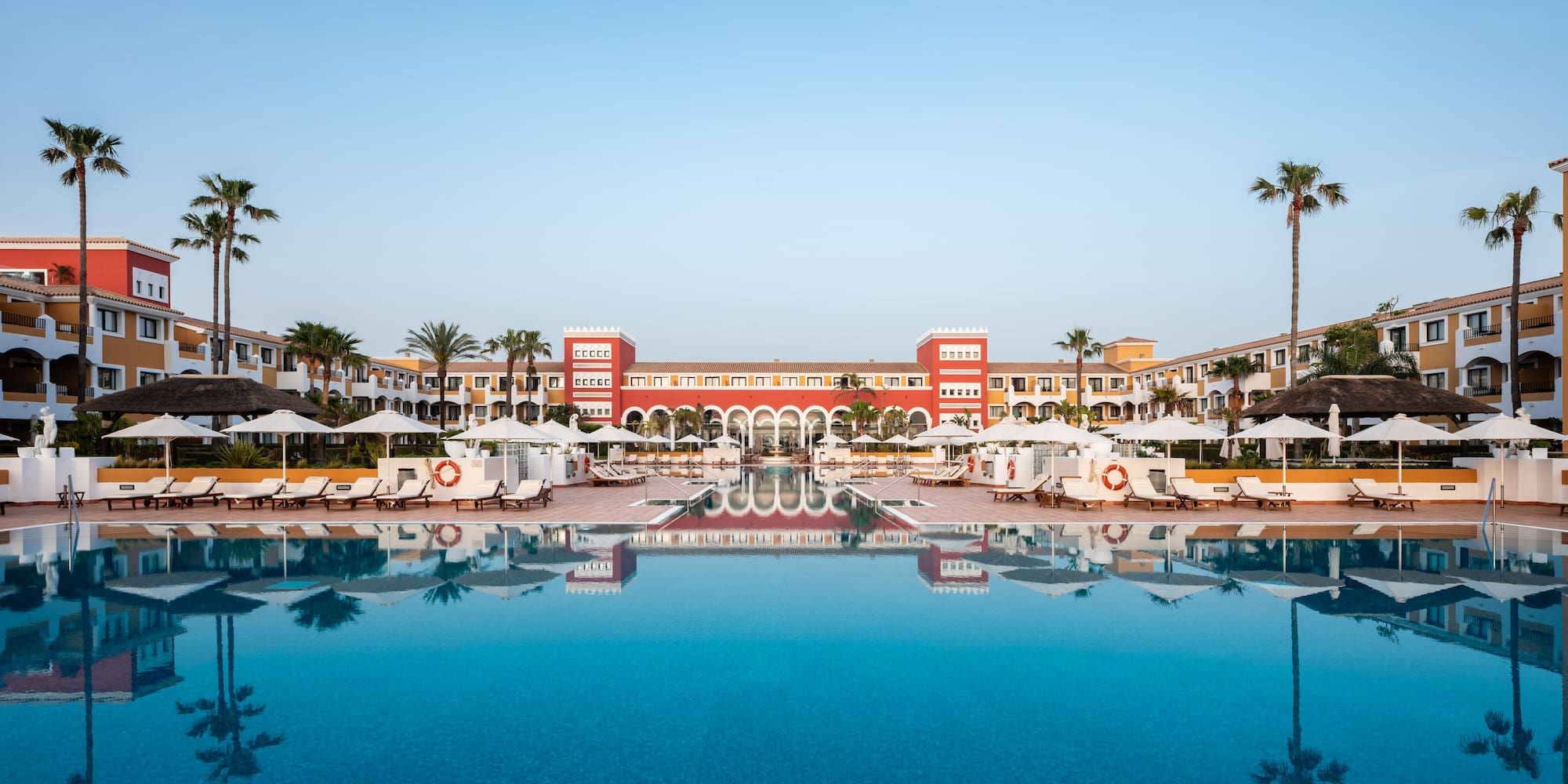a pool with umbrellas and chairs in front of a building