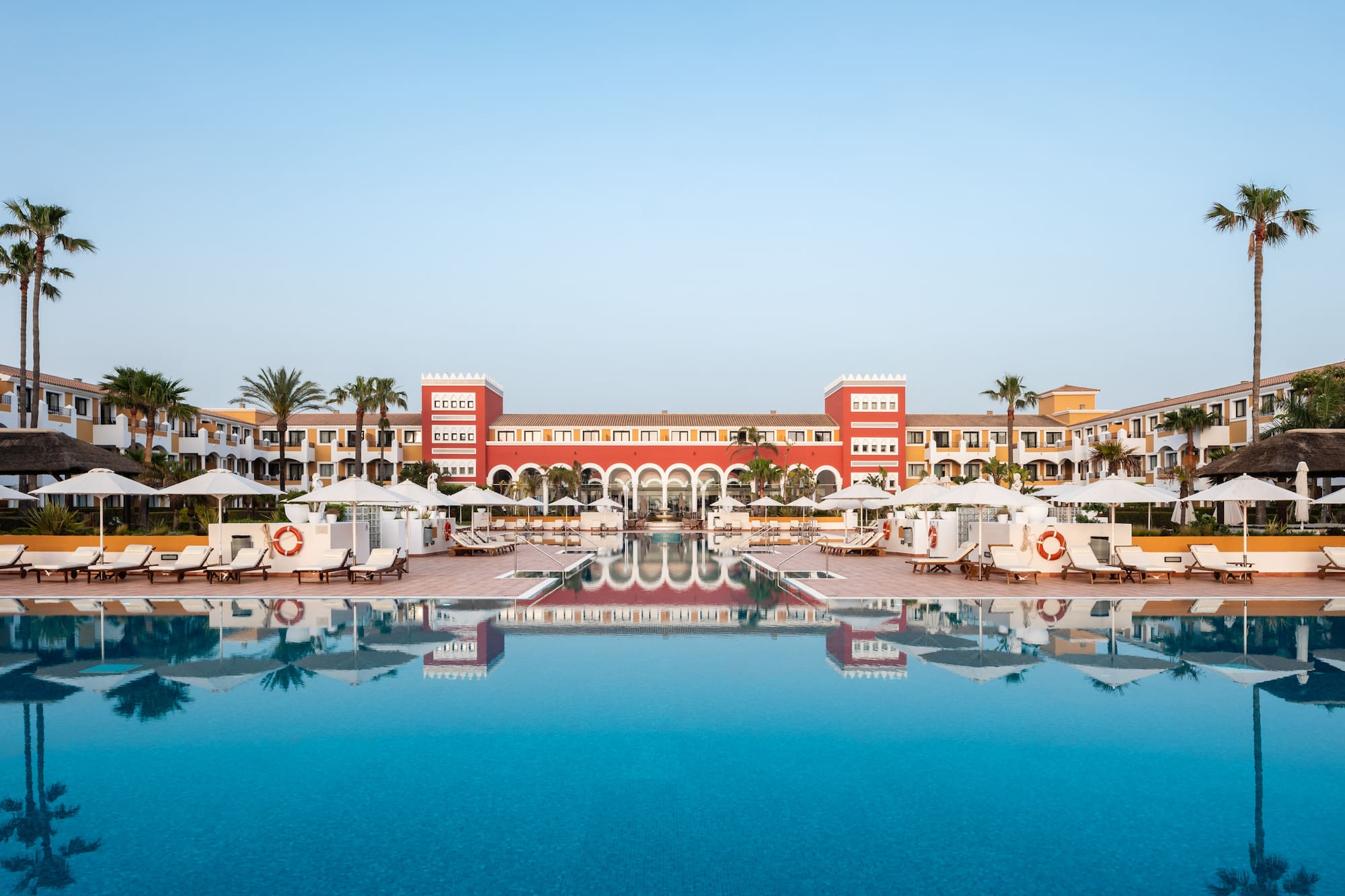 a pool with umbrellas and chairs in front of a building