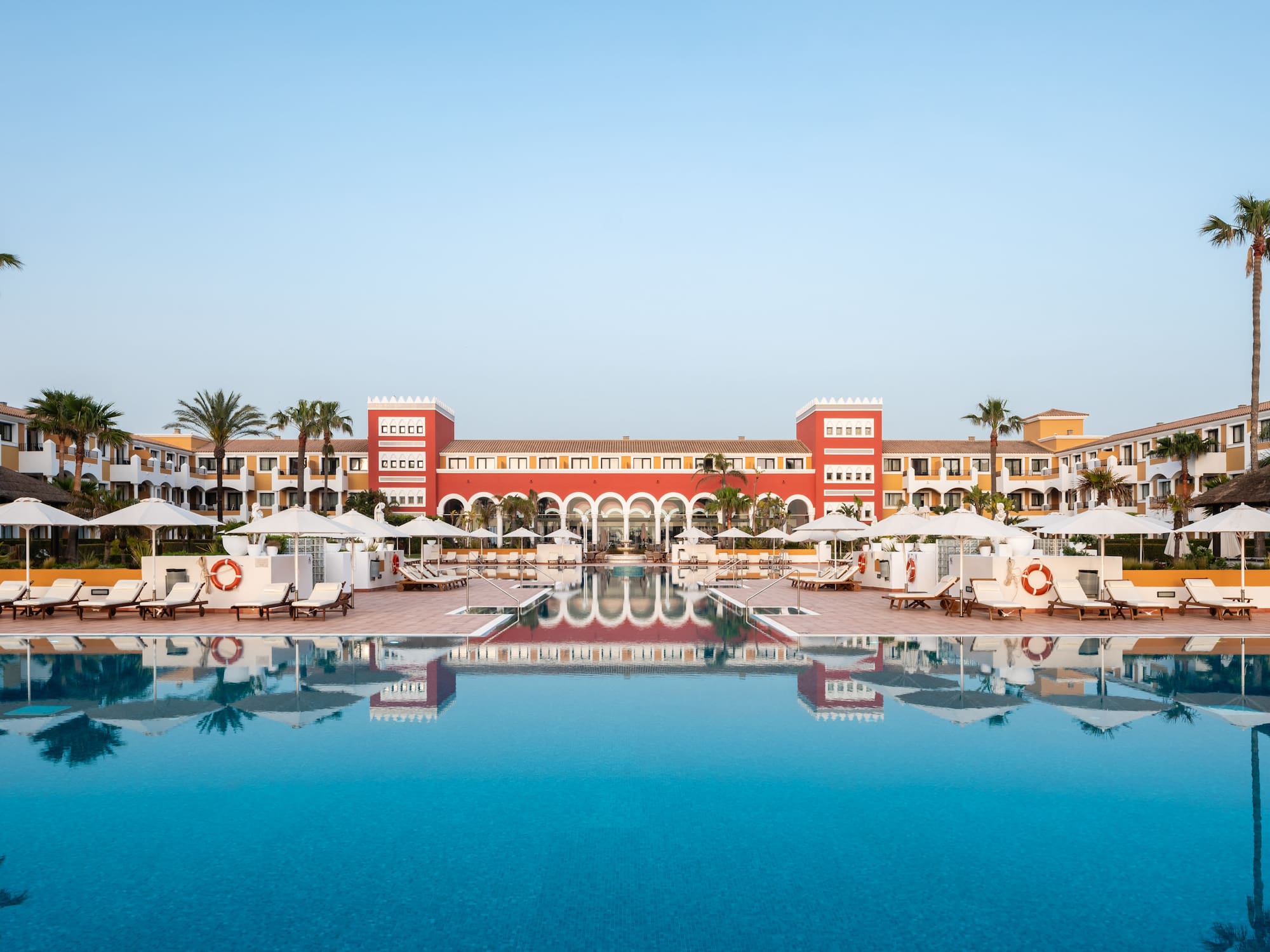 a pool with umbrellas and chairs in front of a building