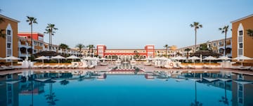 a pool with umbrellas and chairs in front of a building