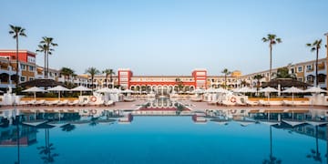 a pool with umbrellas and chairs in front of a building