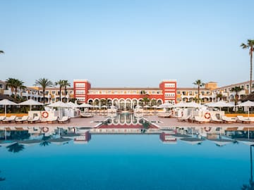 a pool with umbrellas and chairs in front of a building