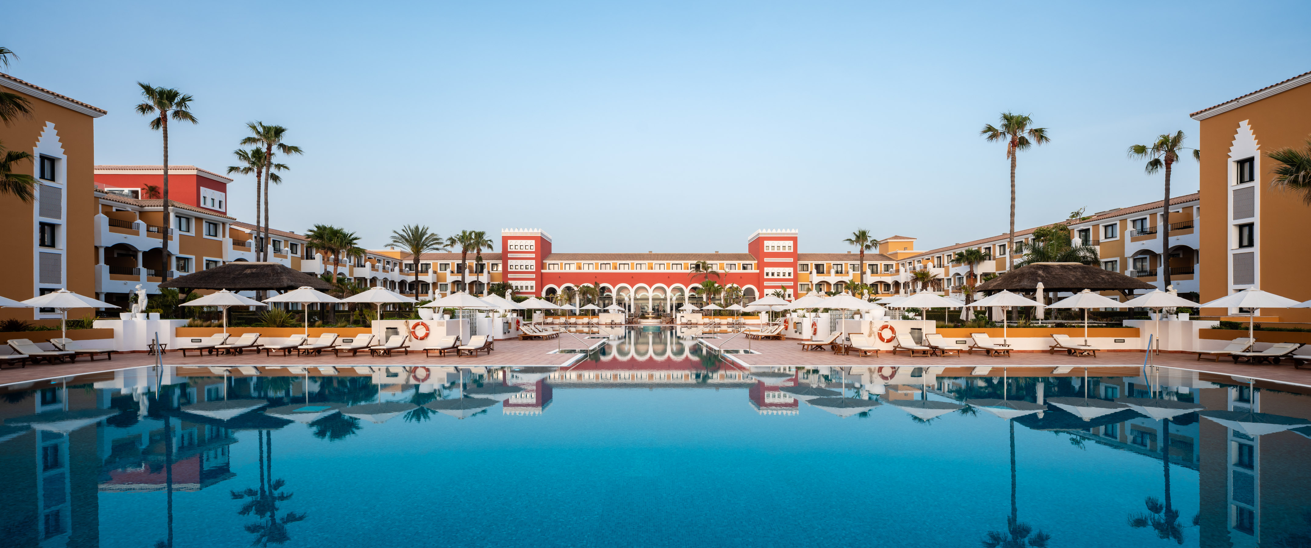 a pool with umbrellas and chairs in front of a building