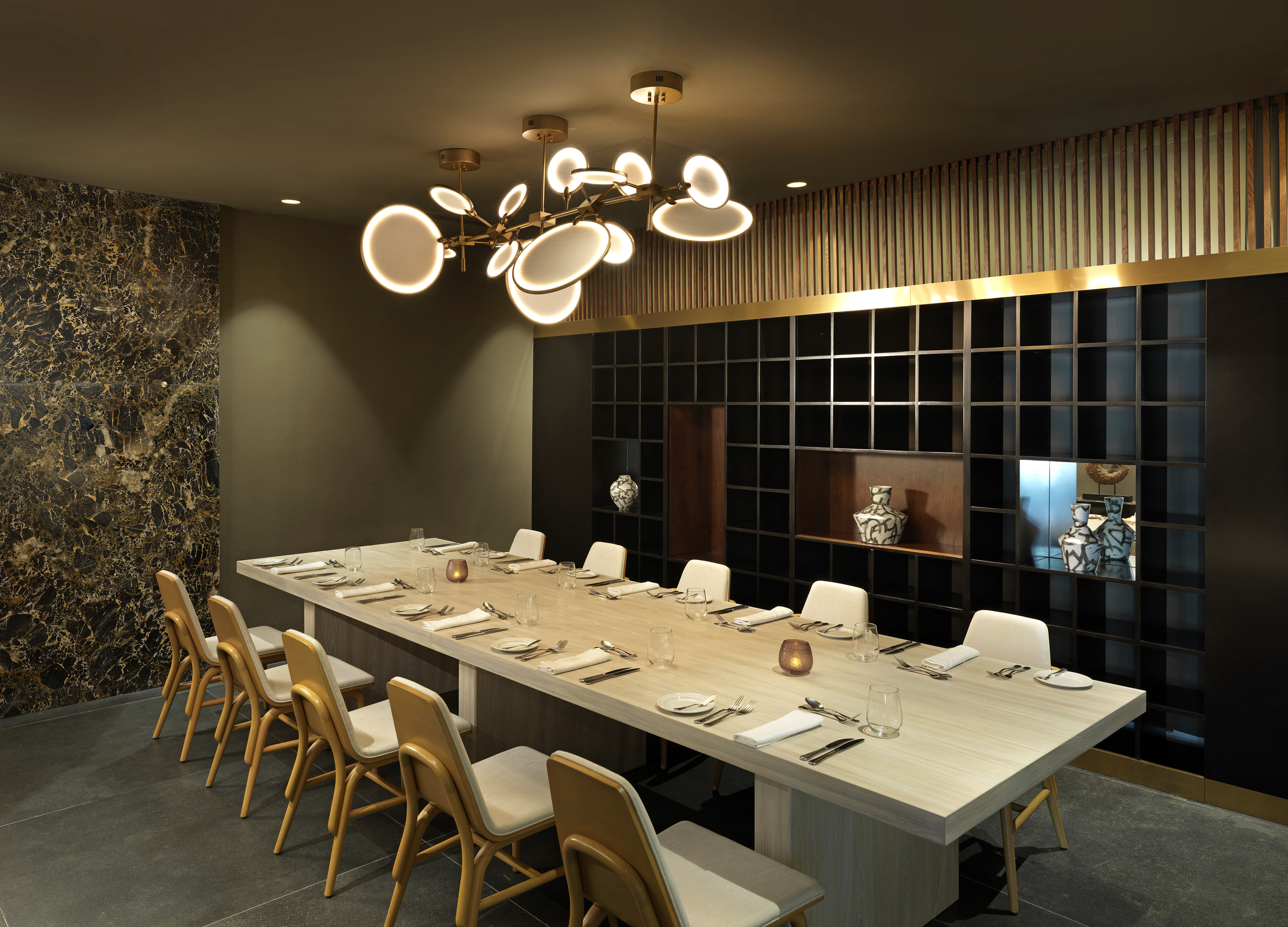 Luxury private dining room with modern chandelier and long dining table.