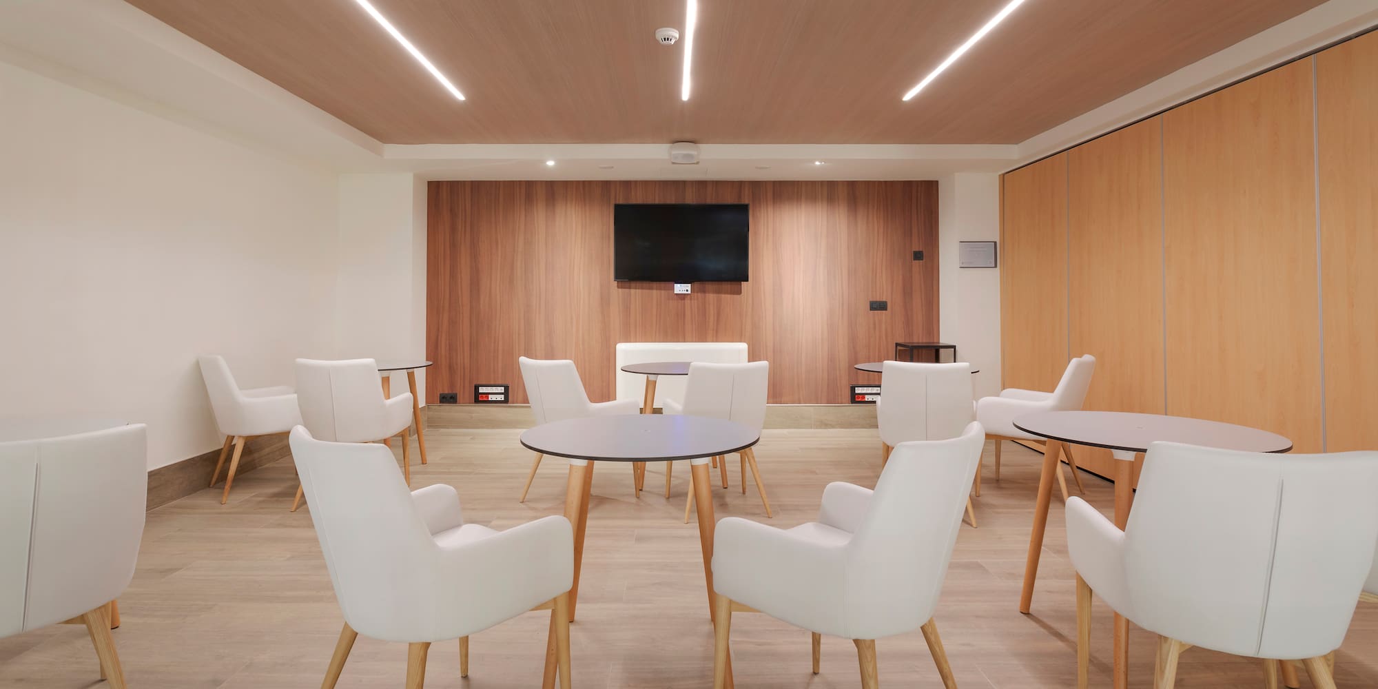 a room with white chairs and a tv