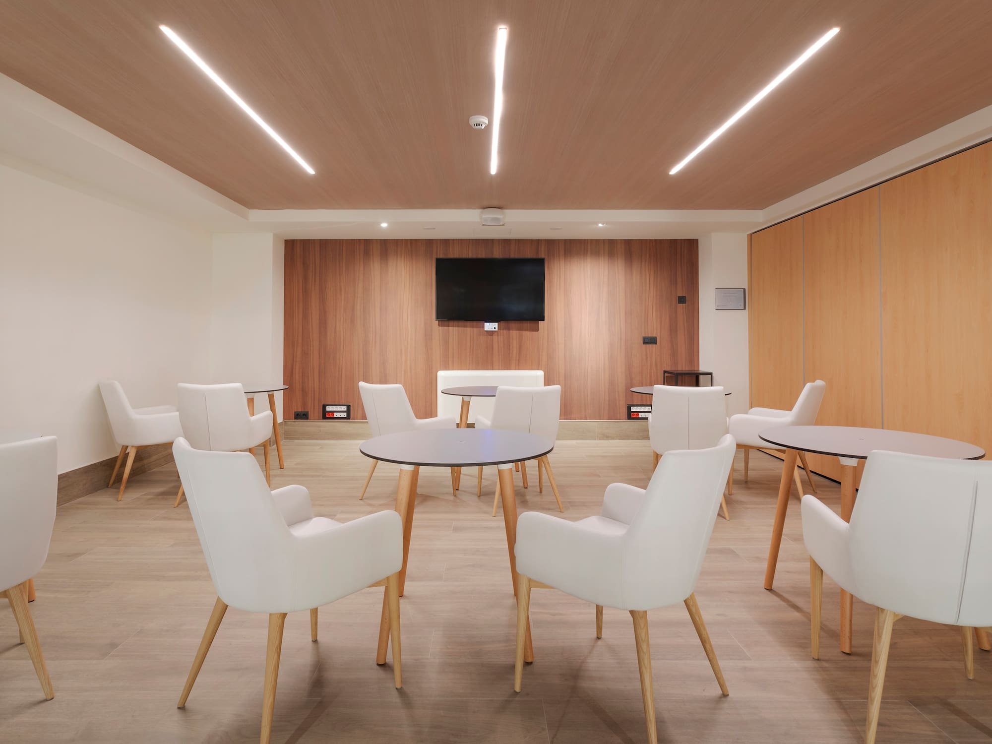 a room with white chairs and a tv