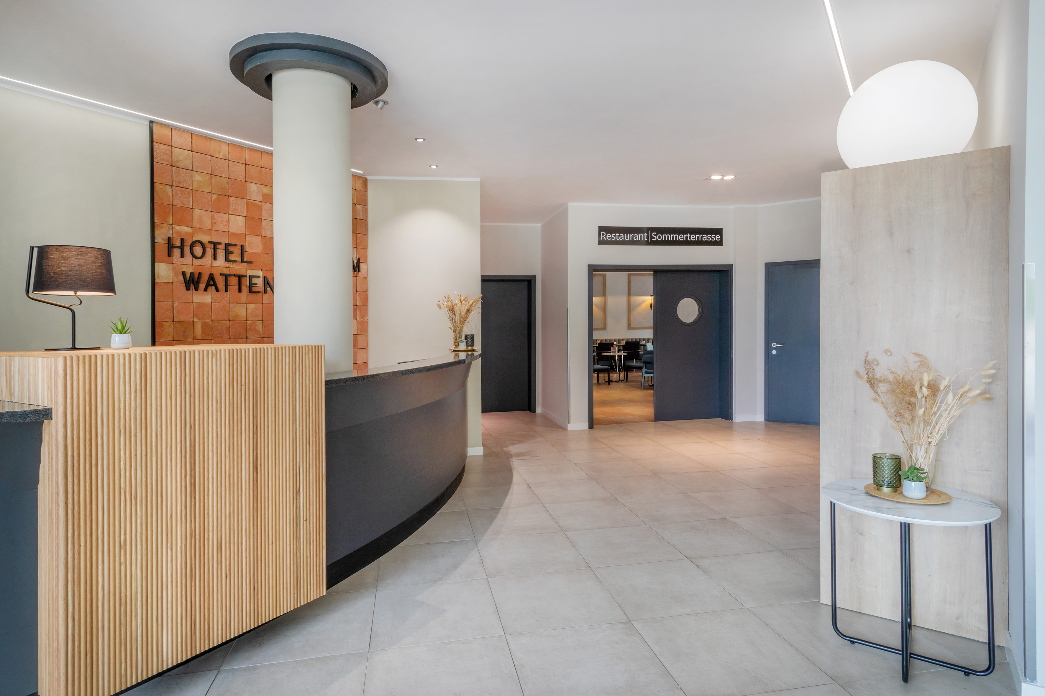 Hotel Watten lobby with modern reception desk and restaurant entrance.