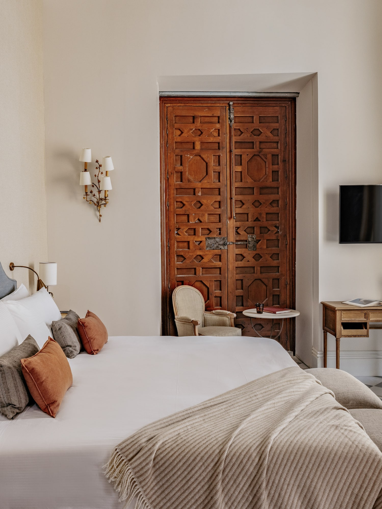 Dormitorio de lujo con cama king-size, cabecero, puerta morisca y suelo de baldosas.