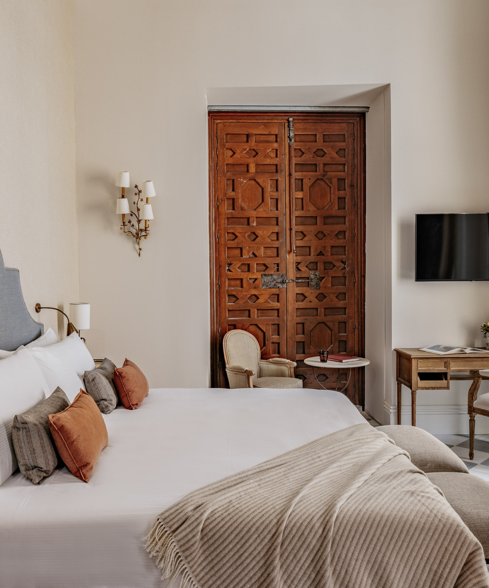 Dormitorio de lujo con cama king-size, cabecero, puerta morisca y suelo de baldosas.