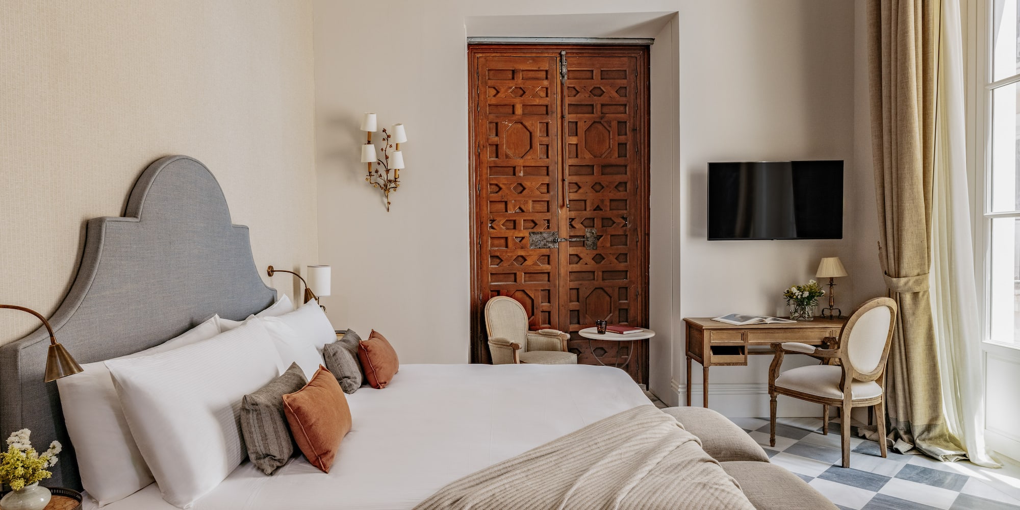 Dormitorio de lujo con cama king-size, cabecero, puerta morisca y suelo de baldosas.