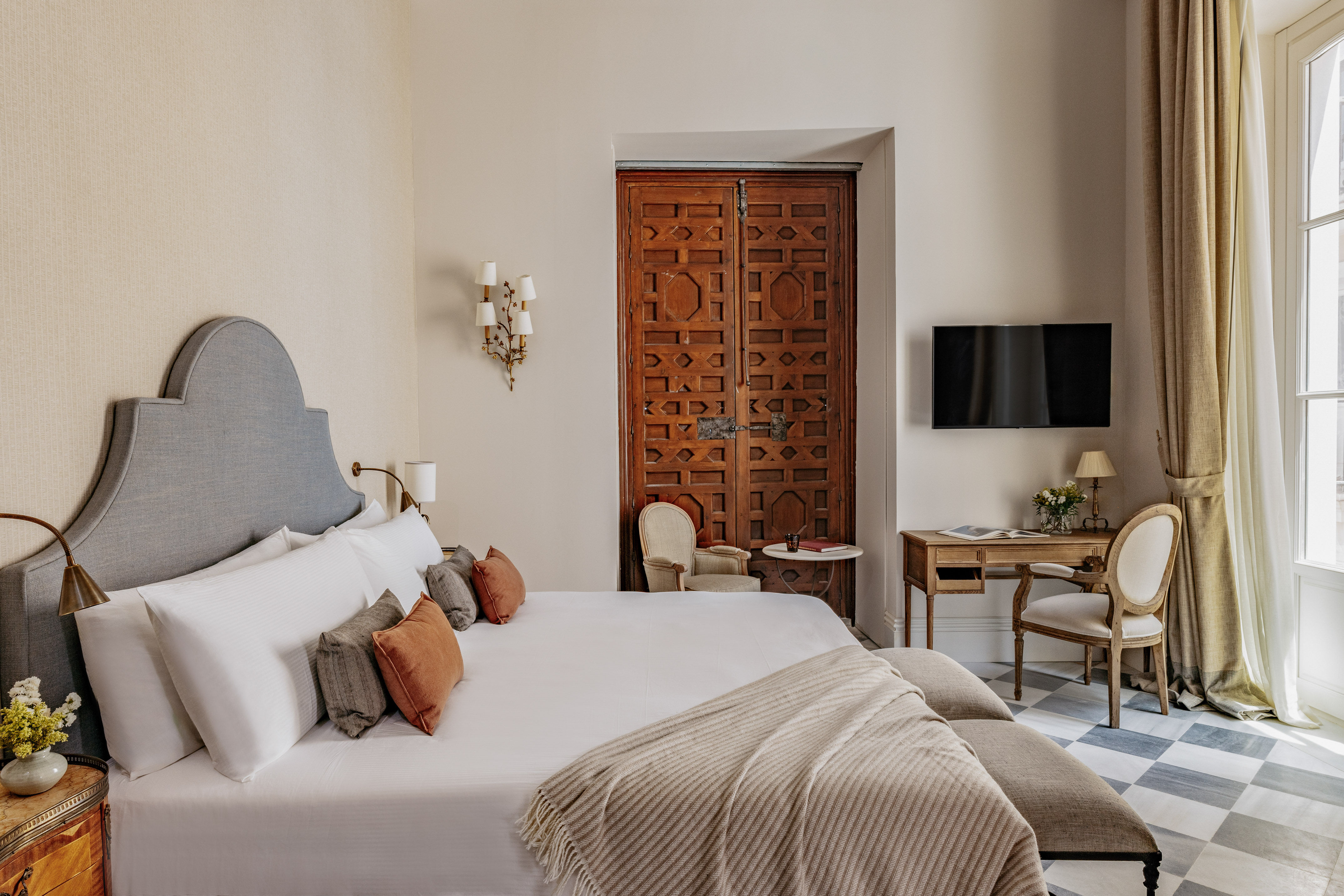 Dormitorio de lujo con cama king-size, cabecero, puerta morisca y suelo de baldosas.