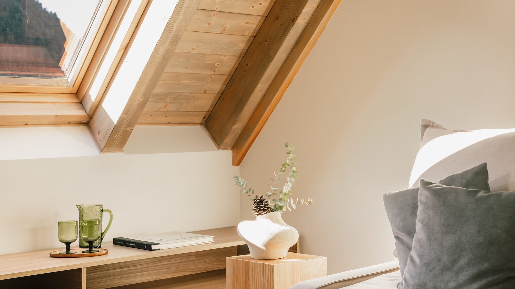 Sloping wooden attic room with bright skylight, cozy sofa, and modern decor.