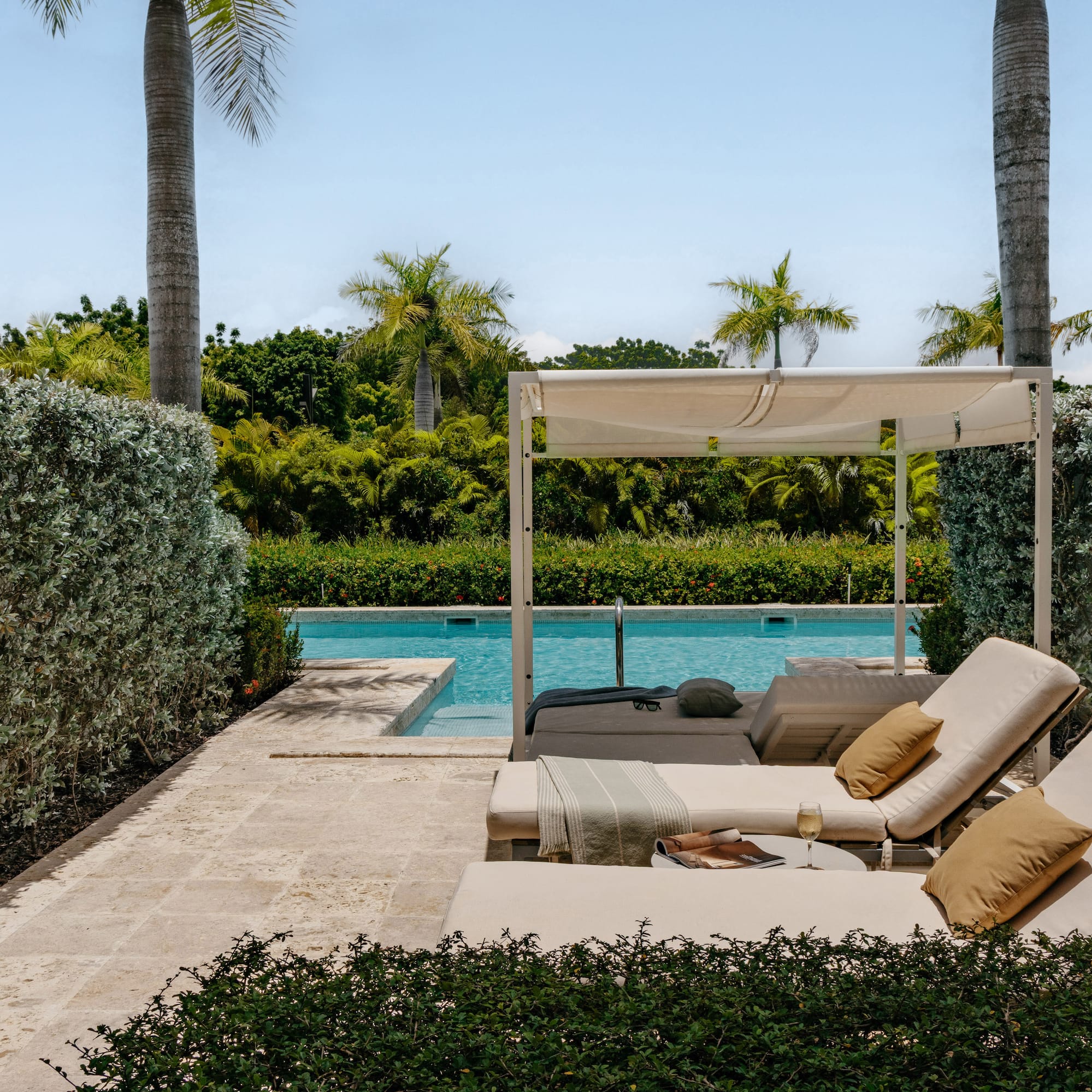 Luxury pool deck with cabana, lounge chairs, and tropical landscaping.