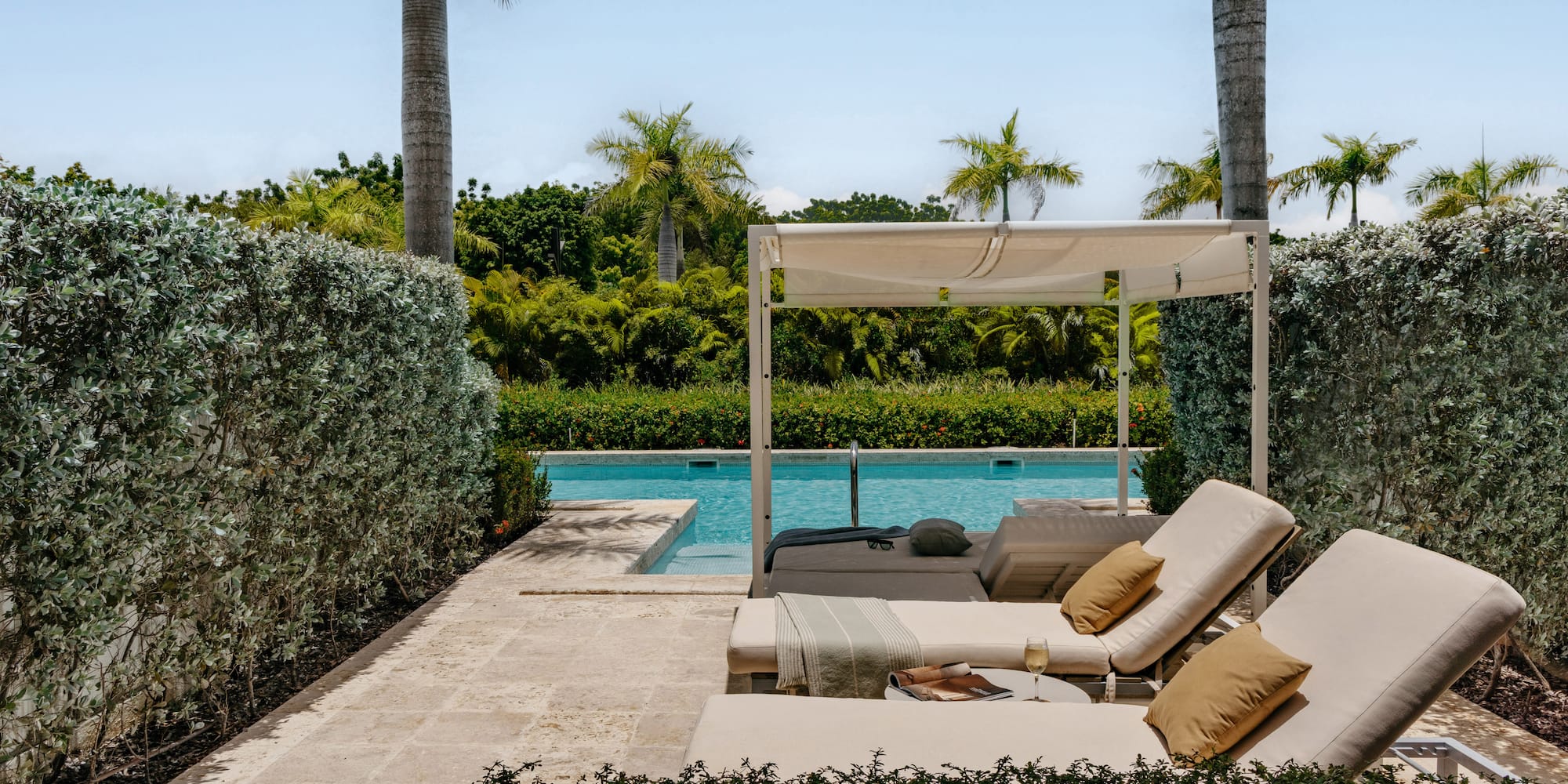 Luxury pool deck with cabana, lounge chairs, and tropical landscaping.