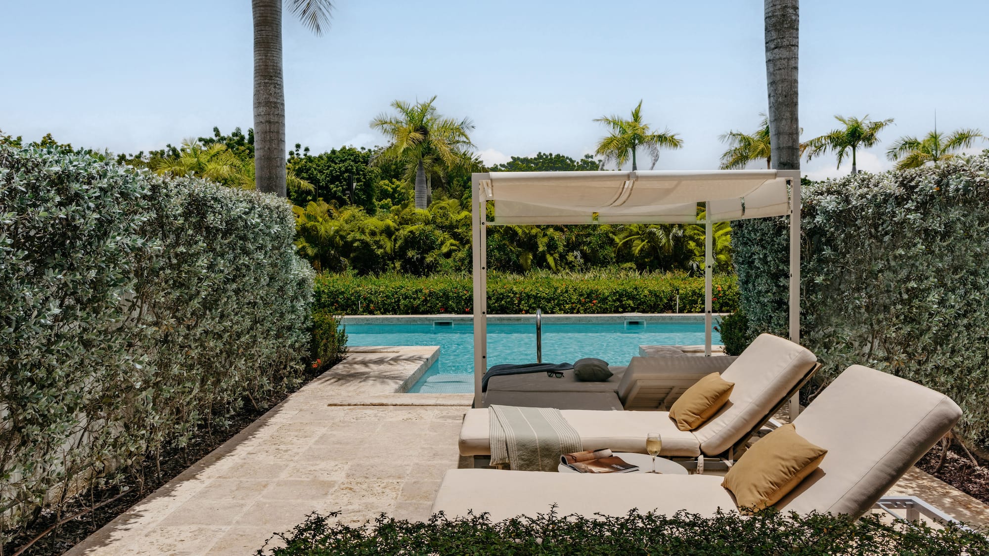 Luxury pool deck with cabana, lounge chairs, and tropical landscaping.