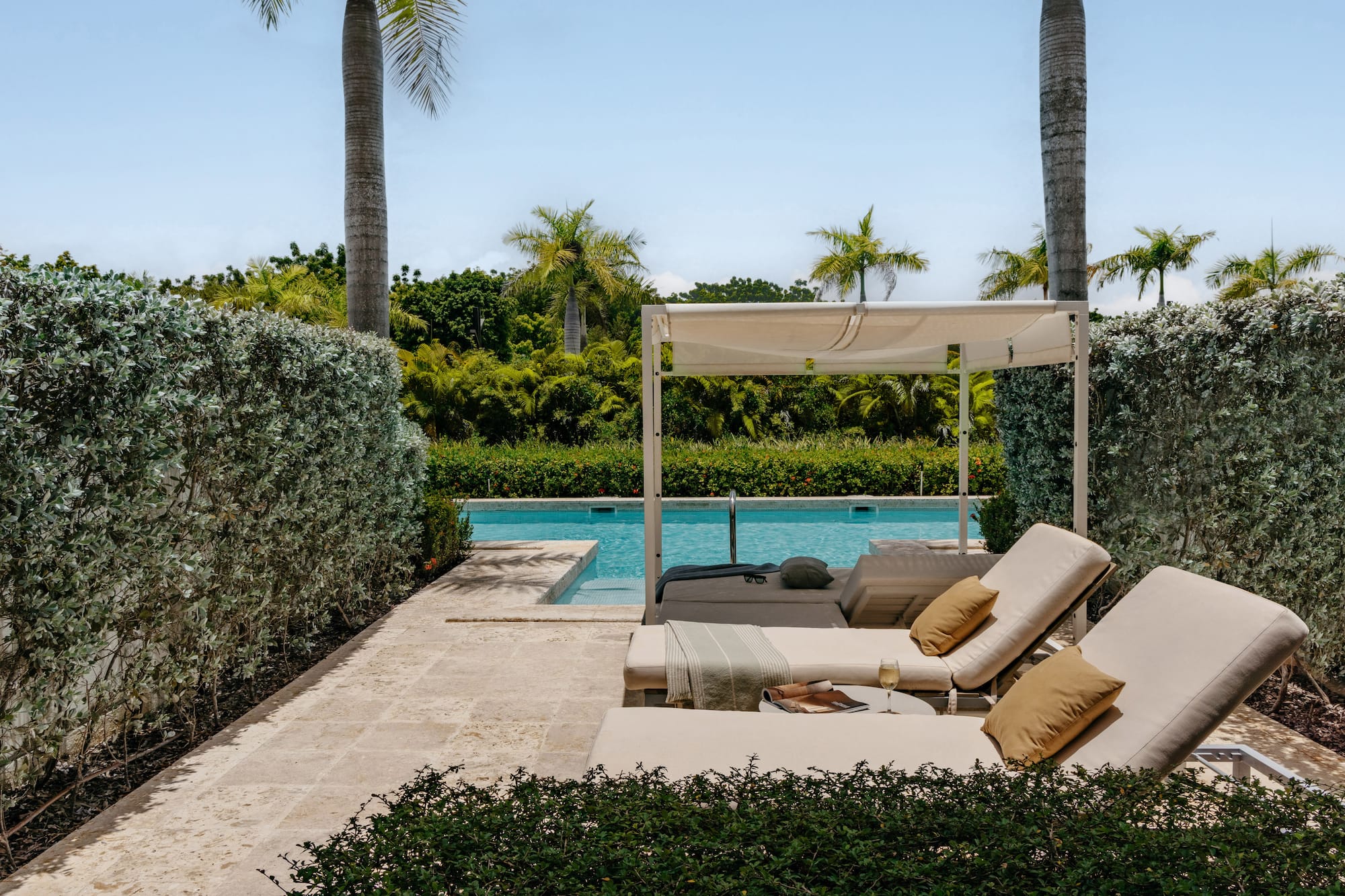 Luxury pool deck with cabana, lounge chairs, and tropical landscaping.